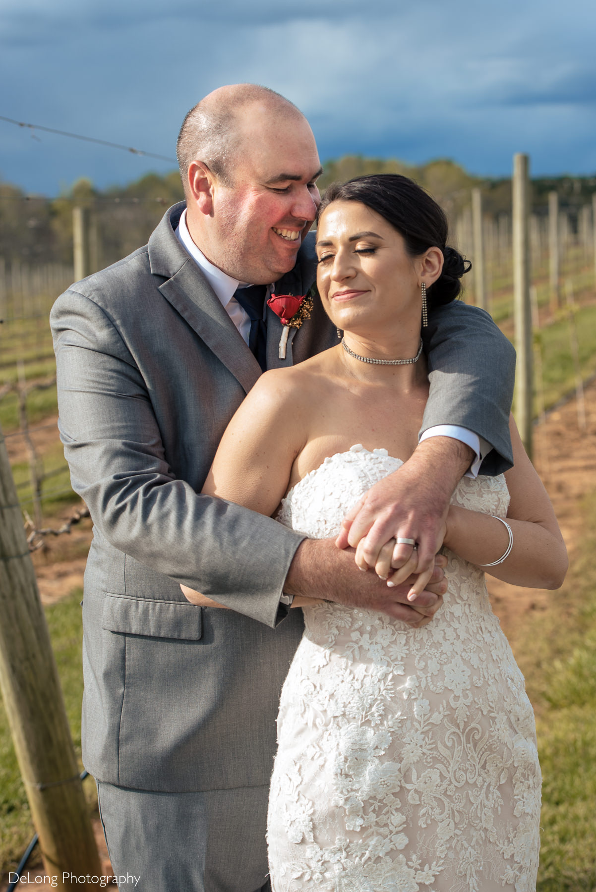 Bride and groom smiling during snuggly portrait at Childress Vineyards by Charlotte Wedding Photographers DeLong Photography