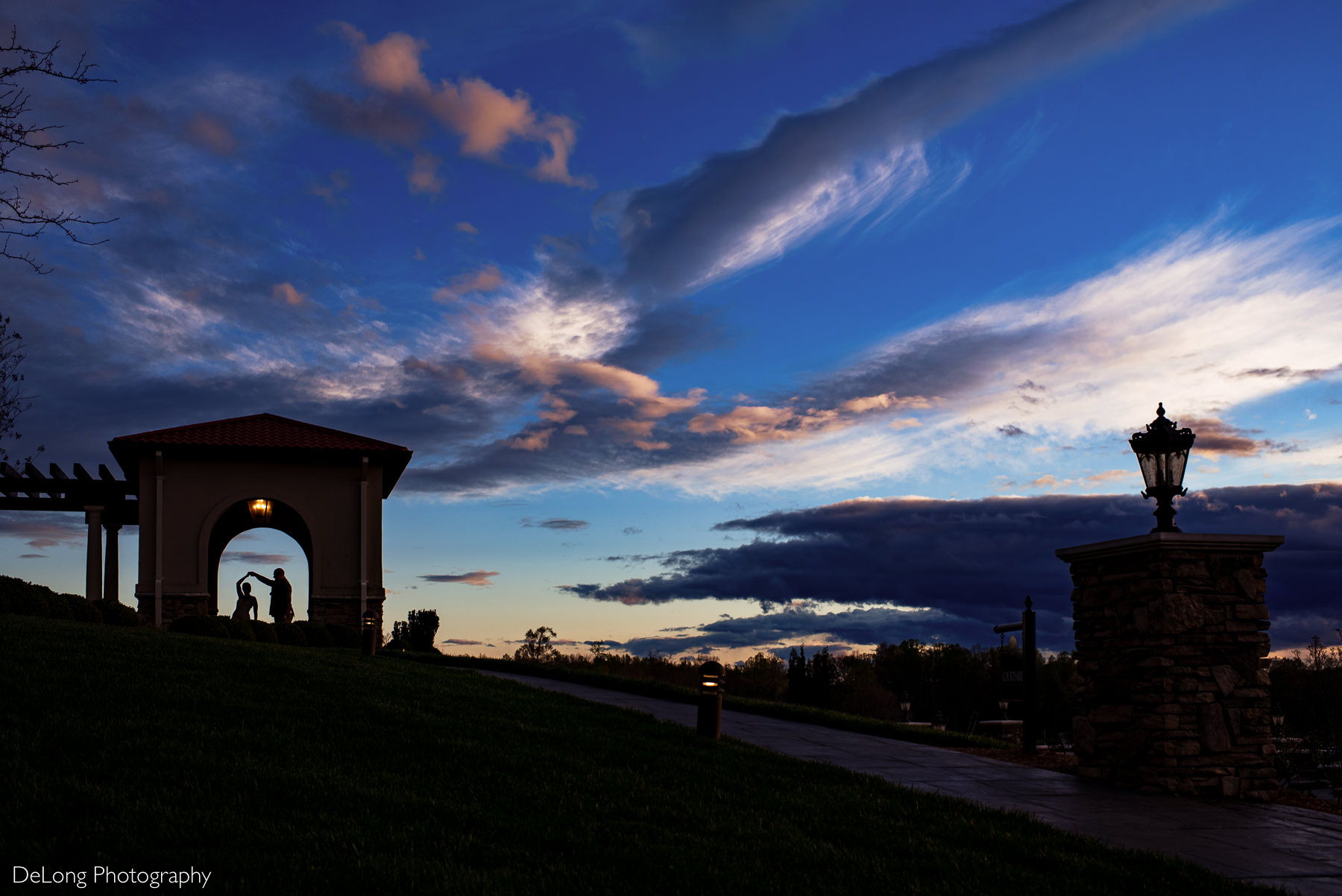 Silhouette at sunset of bride and groom dancing under an archway at Childress Vineyards by Charlotte Wedding Photographers DeLong Photography