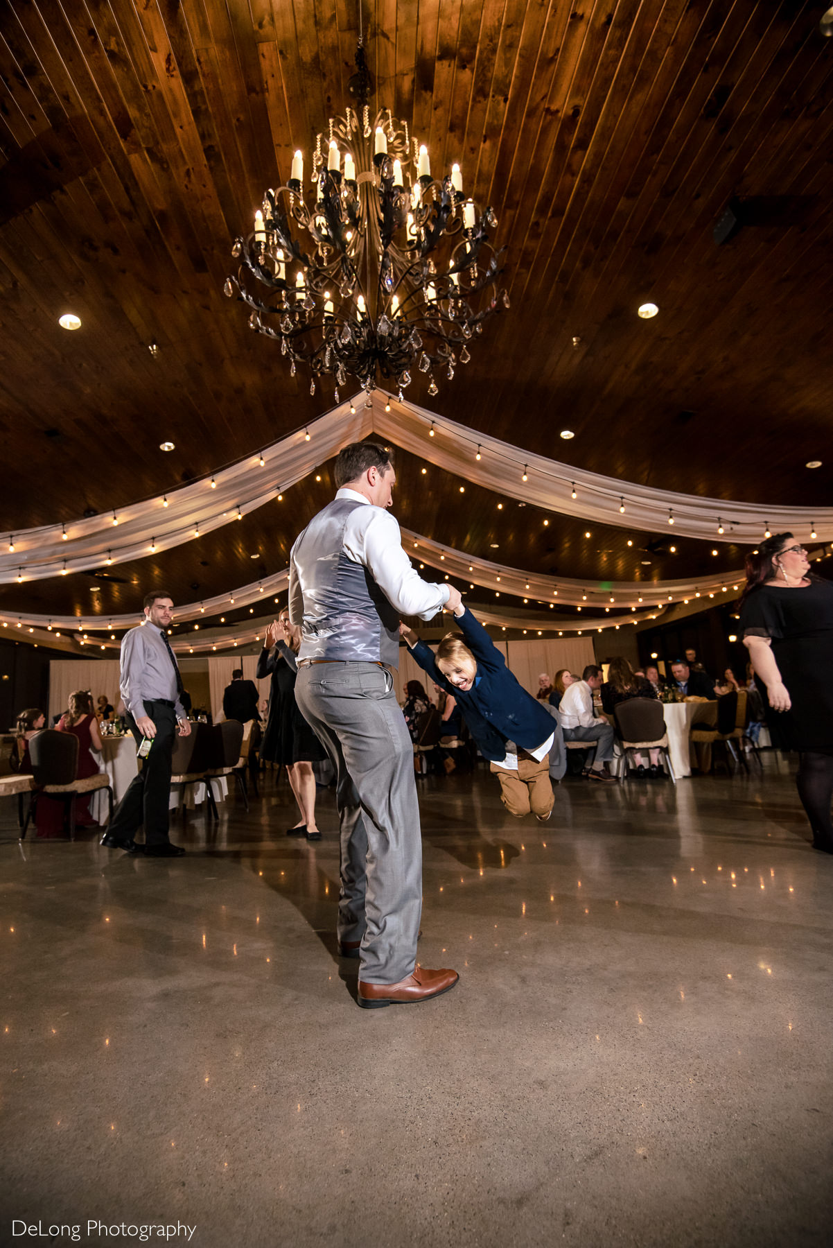 Man swinging child around during reception at Childress Vineyards by Charlotte Wedding Photographers DeLong Photography