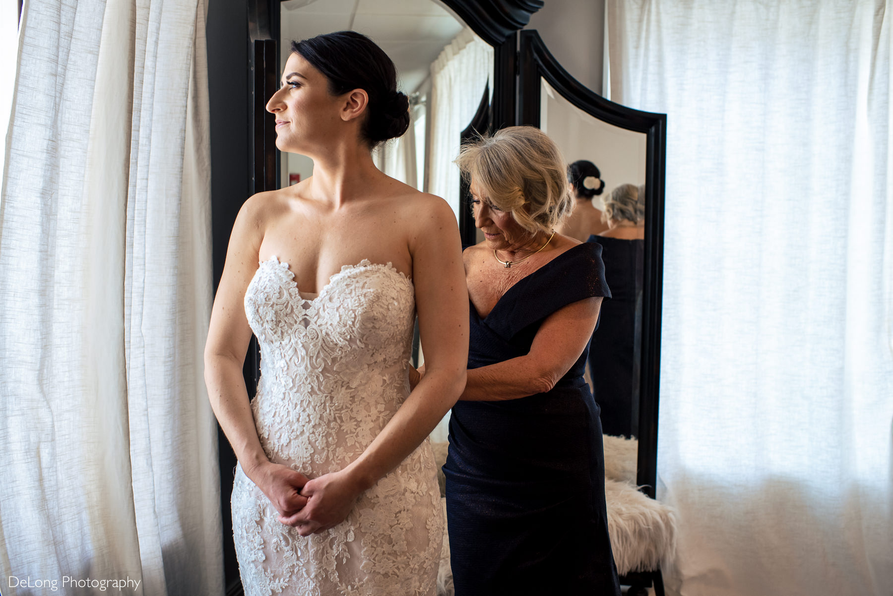Mother of the Bride zipping up bride's dress in the bridal suite at Childress Vineyards by Charlotte Wedding Photographers DeLong Photography
