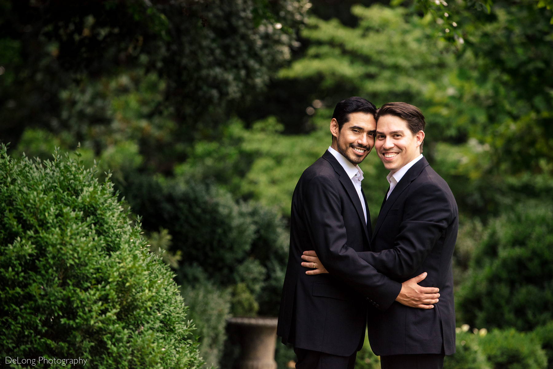 Gay couple with their temples together smiling and looking at the camera in the garden of the Duke Mansion by Charlotte wedding photographers DeLong Photography
