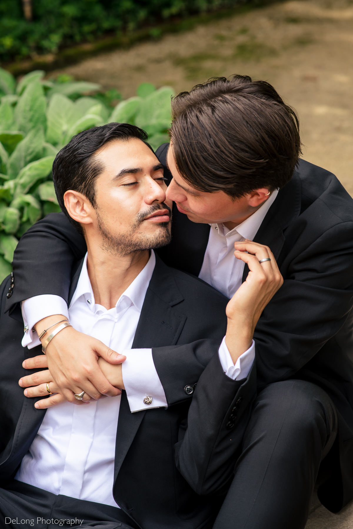 Same-sex couple sharing a tender moment before a kiss in the gardens of the Duke Mansion by Charlotte wedding photographers DeLong Photography