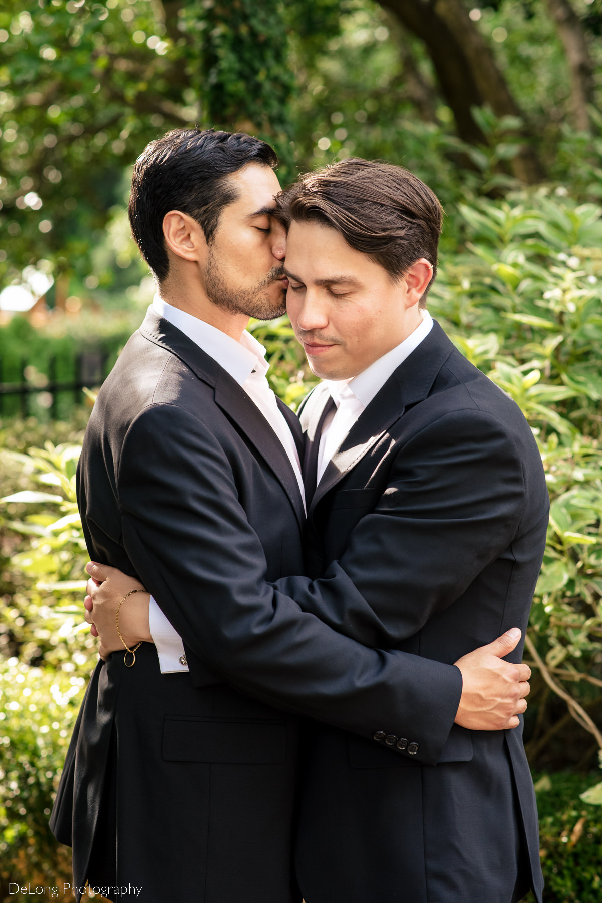 Sweet portrait of a groom receiving a kiss from his husband gentle smiling with his eyes closed at the Duke Mansion by Charlotte wedding photographers DeLong Photography
