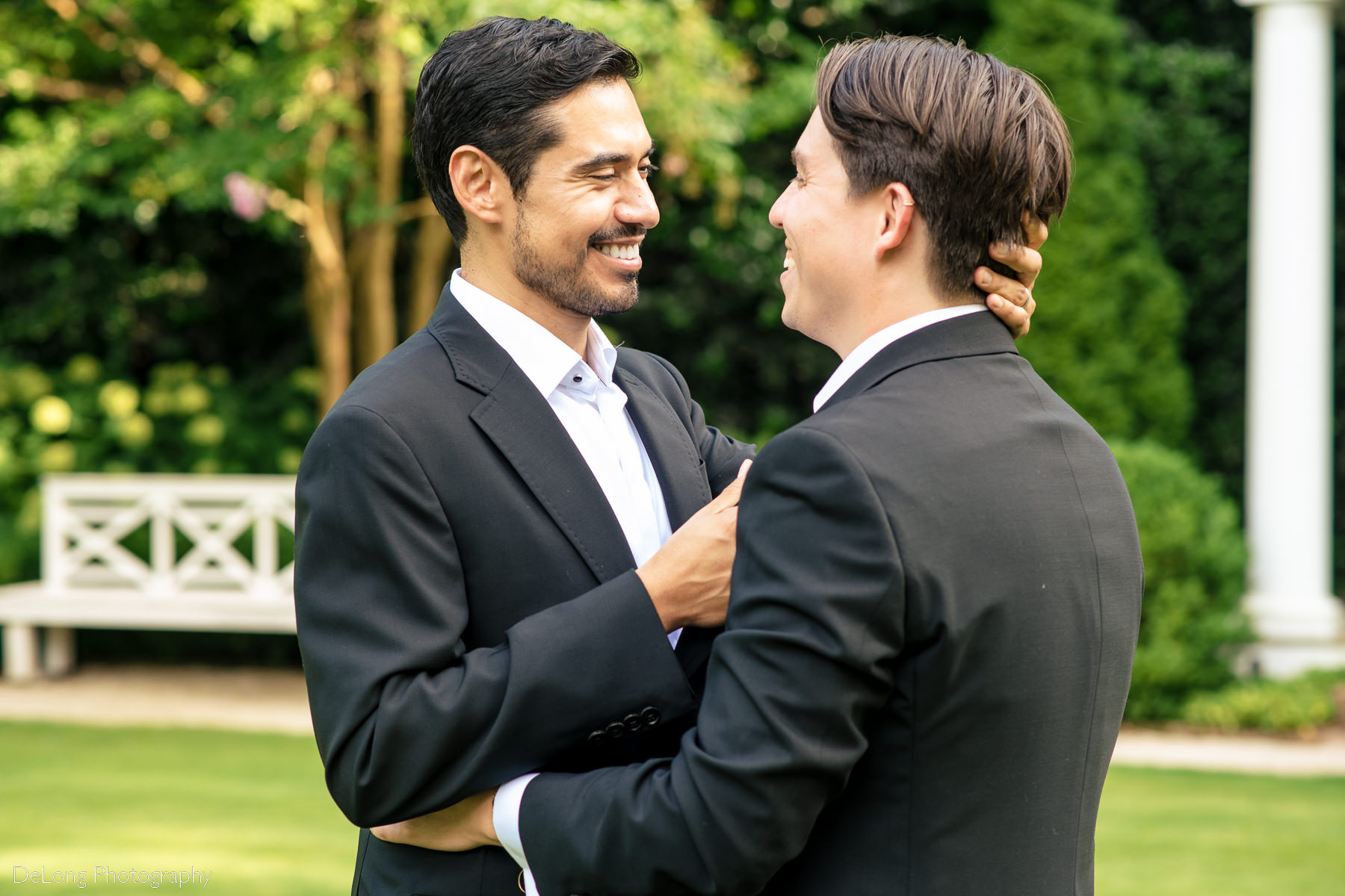 Candid moment of grooms laughing and smiling together in the gardens of the Duke Mansion by Charlotte wedding photographers DeLong Photography