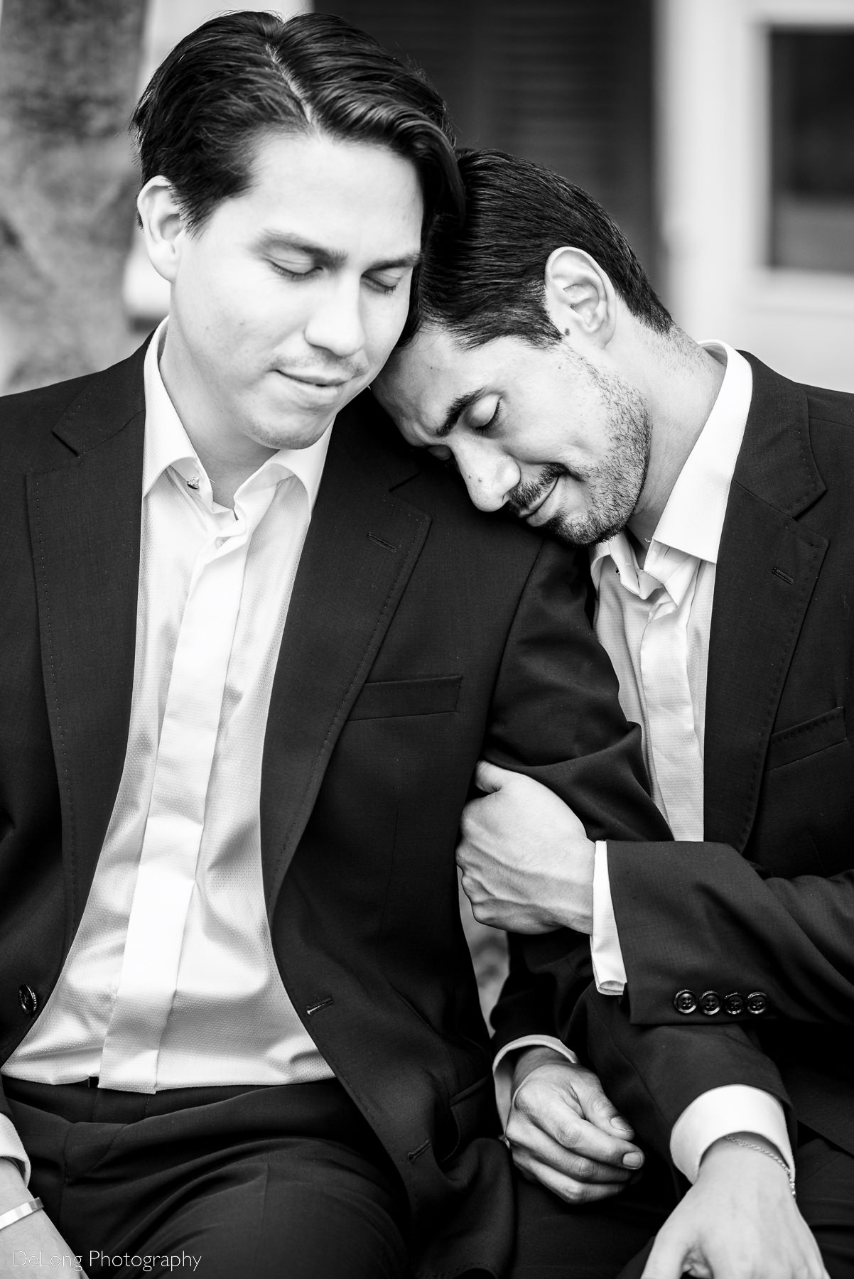 Black and white portrait of two grooms taking in a quiet moment together seated outside the Duke Mansion by Charlotte wedding photographers DeLong Photography