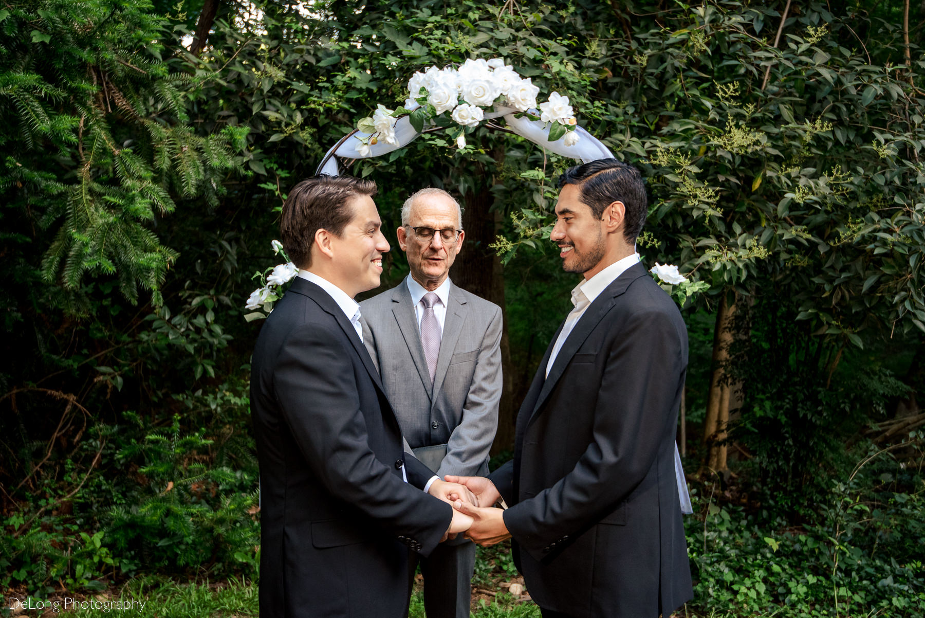 Two grooms holding hands smiling at one another before their ceremony by Charlotte wedding photographers DeLong Photography
