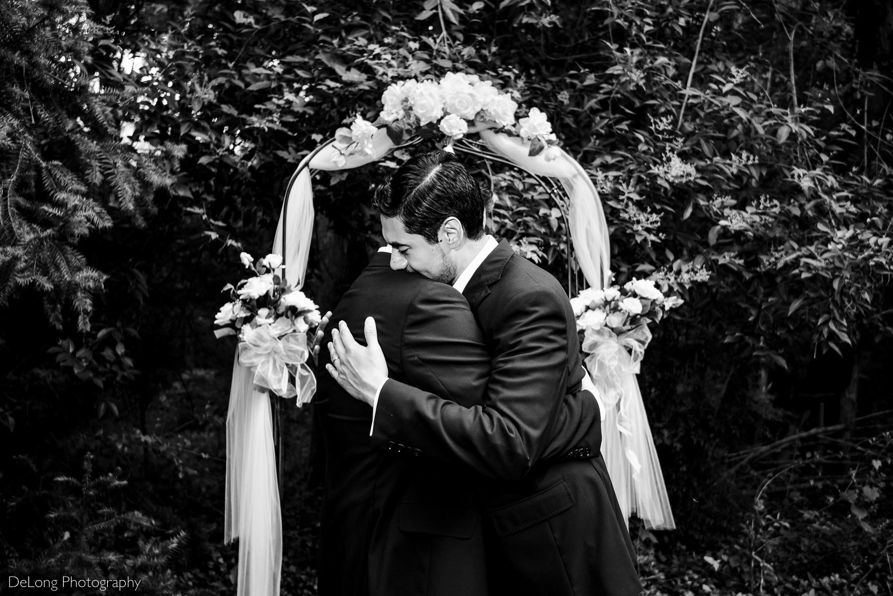 Black and white photograph of two grooms hugging after their first kiss by Charlotte wedding photographers DeLong Photography