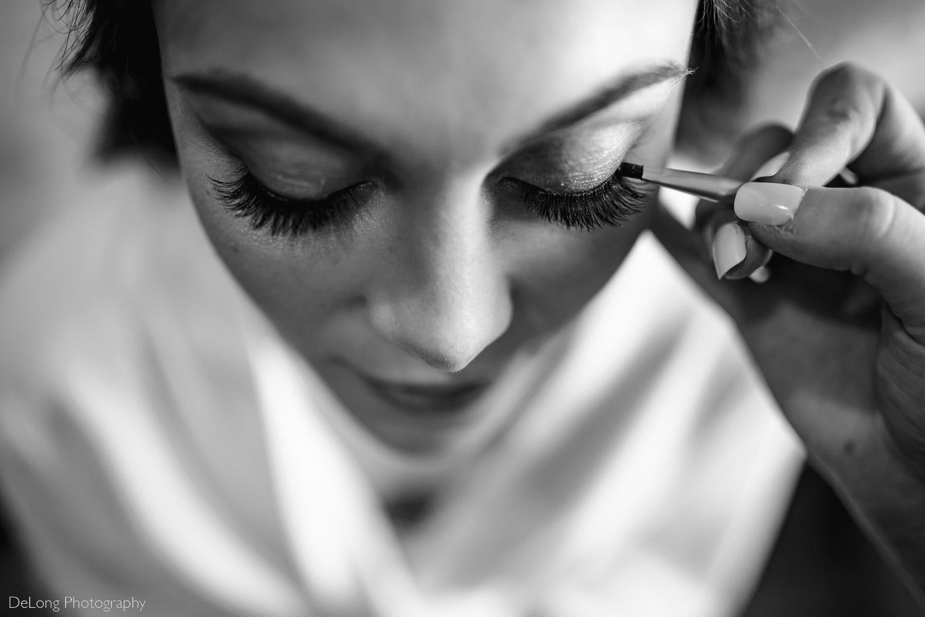 Black and white top-down view of the bride having her eyeliner done, showing off her long lashes by Charlotte Wedding Photographers DeLong Photography