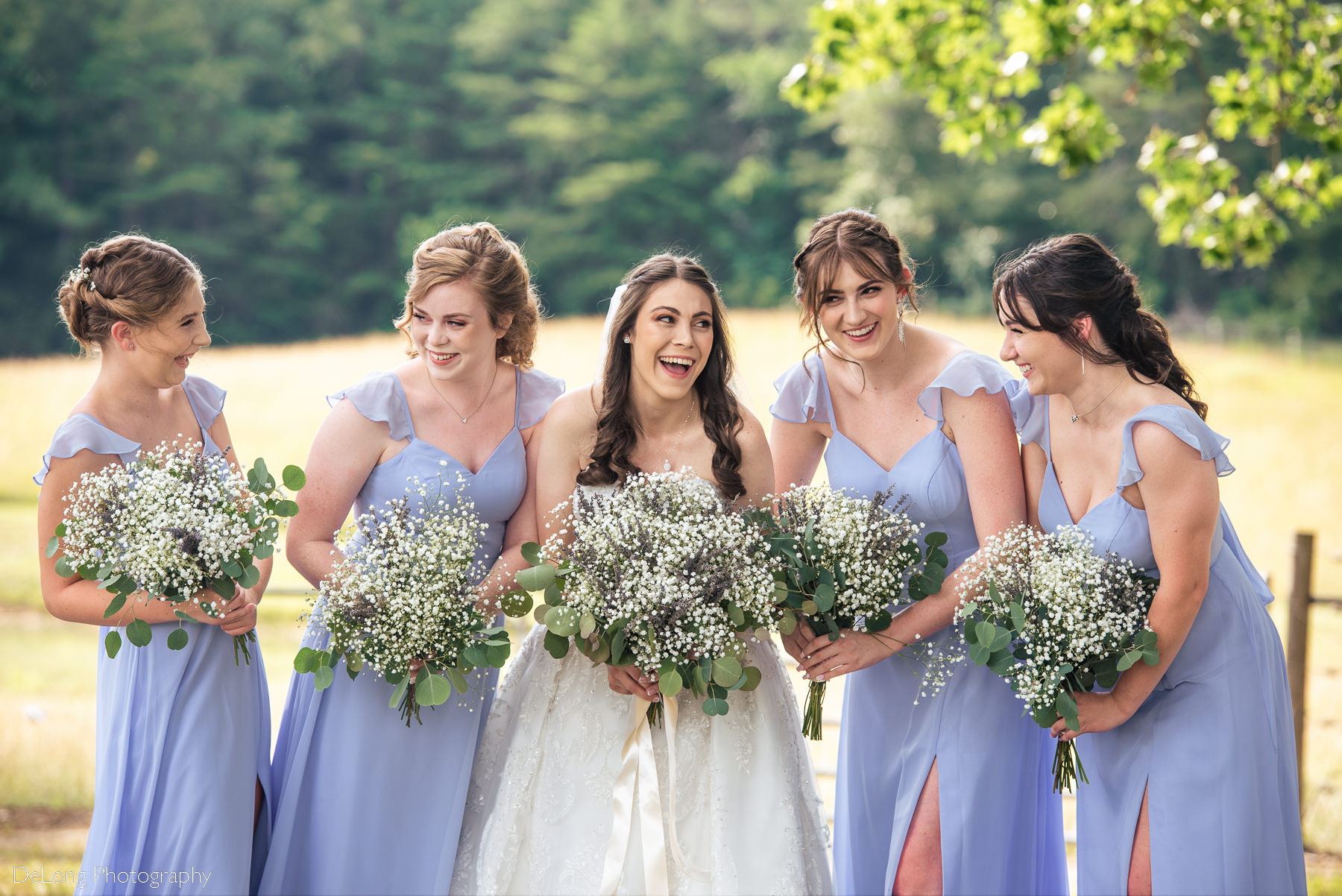 Outdoor photograph of a bride laughing and smiling with her bridesmaids at Lady Bird Farms by Charlotte Wedding Photographers DeLong Photography