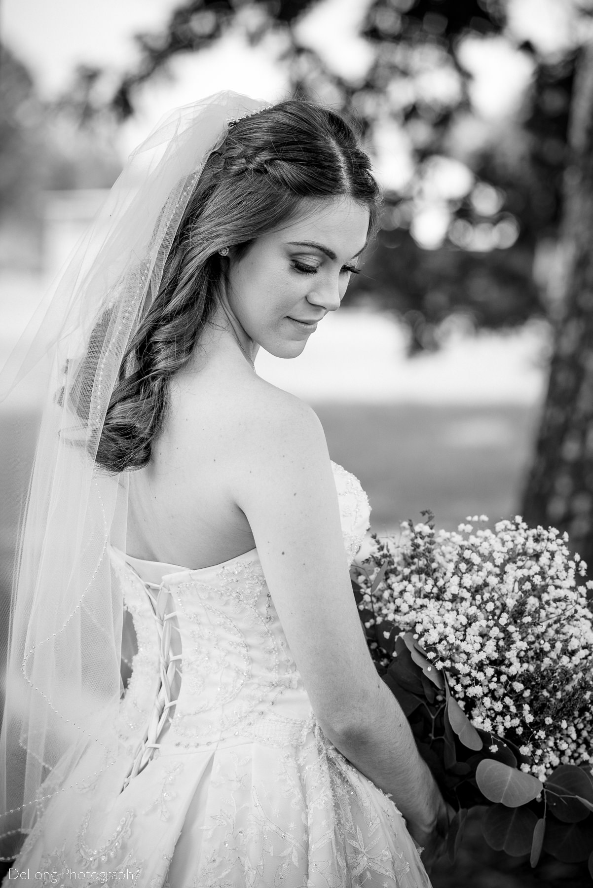 Black and white bridal portrait of bride showing off the back of her dress and veil by Charlotte Wedding Photographers DeLong Photography