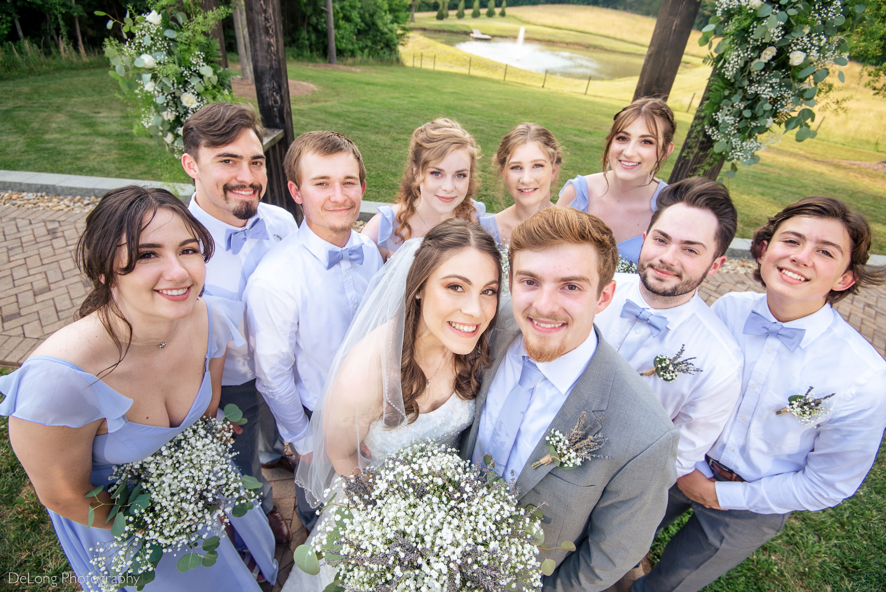 Top-down photograph of wedding party grouped close together smiling up at the camera by Charlotte Wedding Photographers DeLong Photography