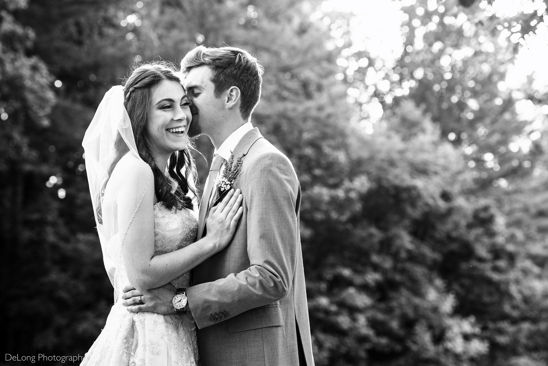 Black and white couple's portrait of bride laughing while groom whispers in her ear by Charlotte Wedding Photographers DeLong Photography