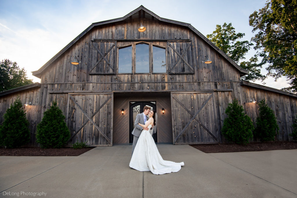 A groom dipping his bride in front of the barn at Lady Bird Farms by Charlotte Wedding Photographers DeLong Photography