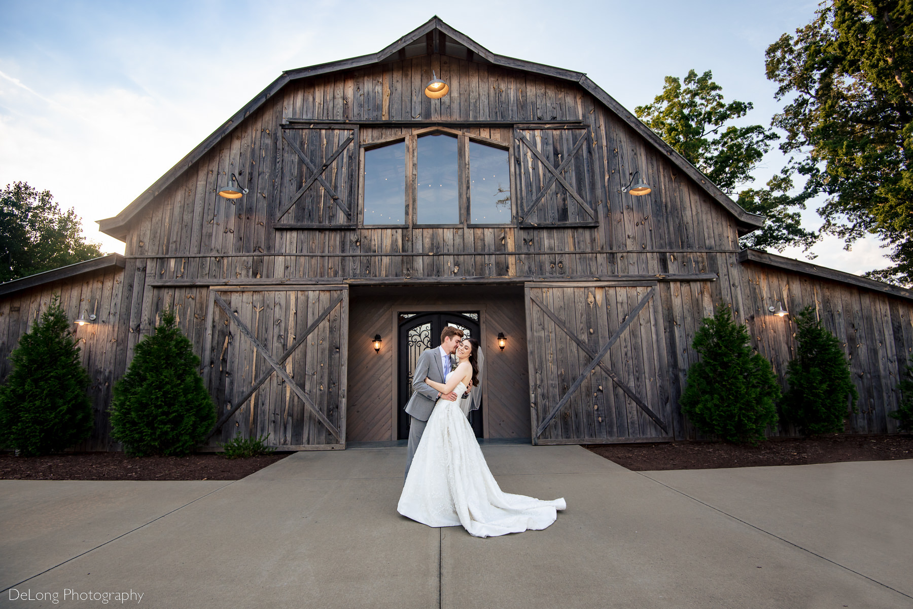 Groom giving his bride a gentle dip in front of the barn at Lady Bird Farms by Charlotte Wedding Photographers DeLong Photography