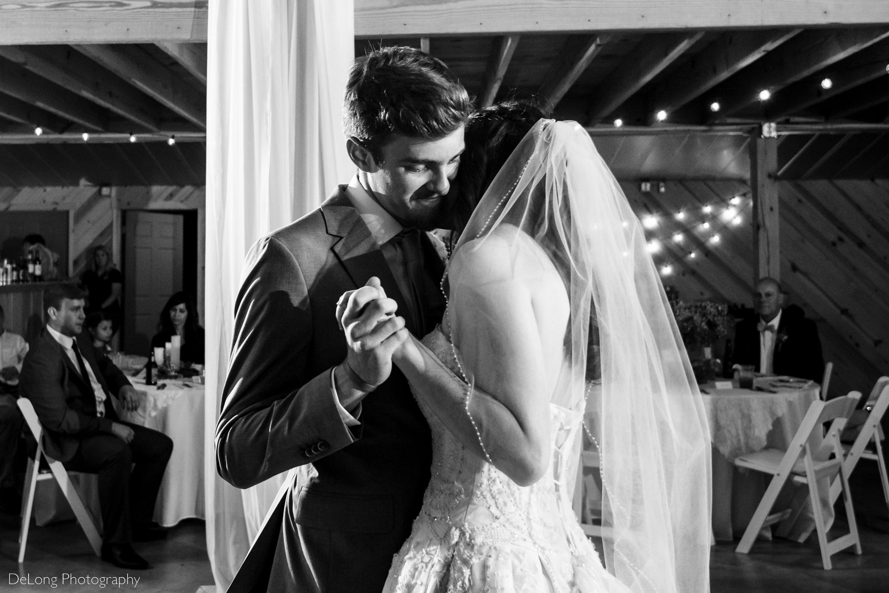 Black and white image of groom dancing cheek-to-cheek with his bride during their first dance at Lady Bird Farms by Charlotte Wedding Photographers DeLong Photography