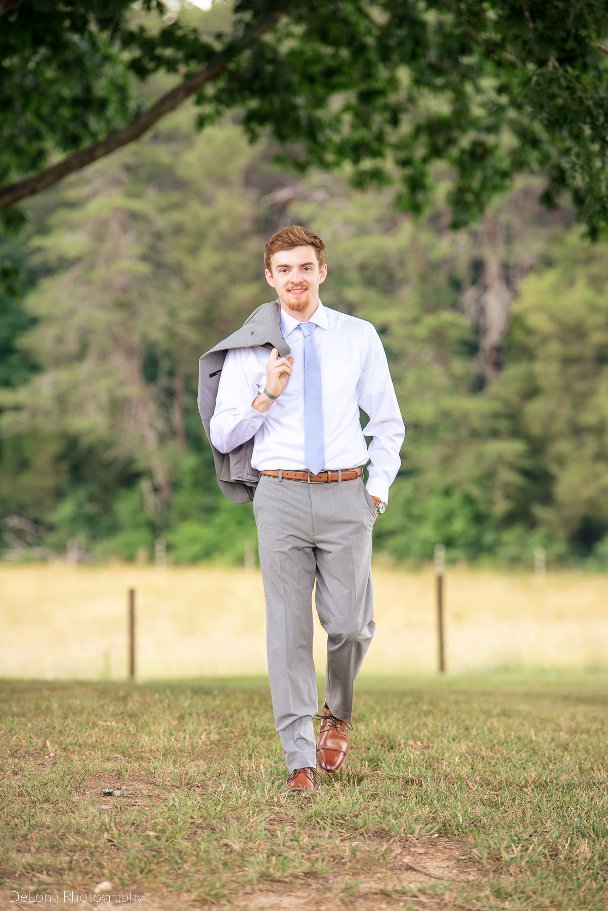 Portrait of groom walking with his grey suit jacket over his shoulder at Lady Bird Farms by Charlotte Wedding Photographers DeLong Photography