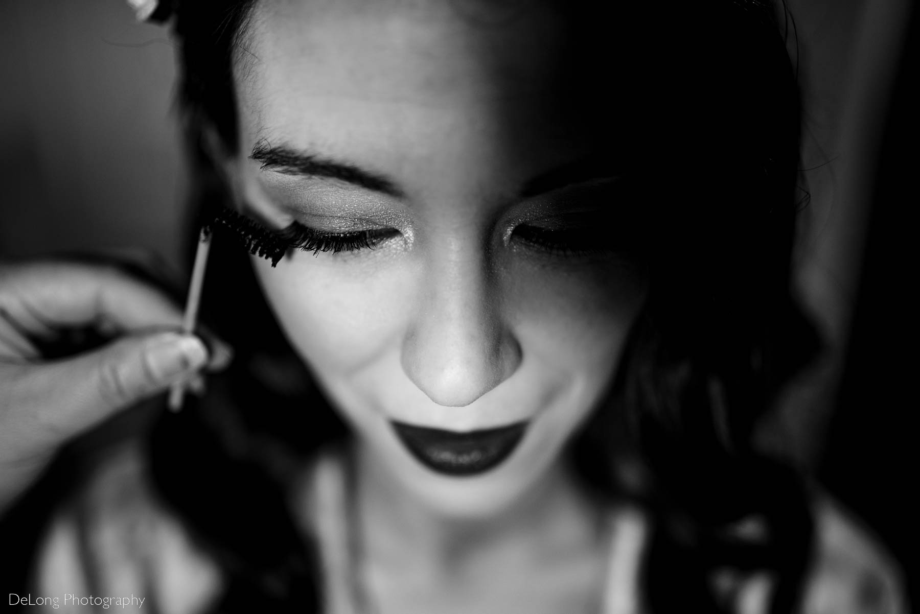 Black and white up close photograph of the bride having mascara applied to her eyelashes by Charlotte wedding photographers DeLong Photography