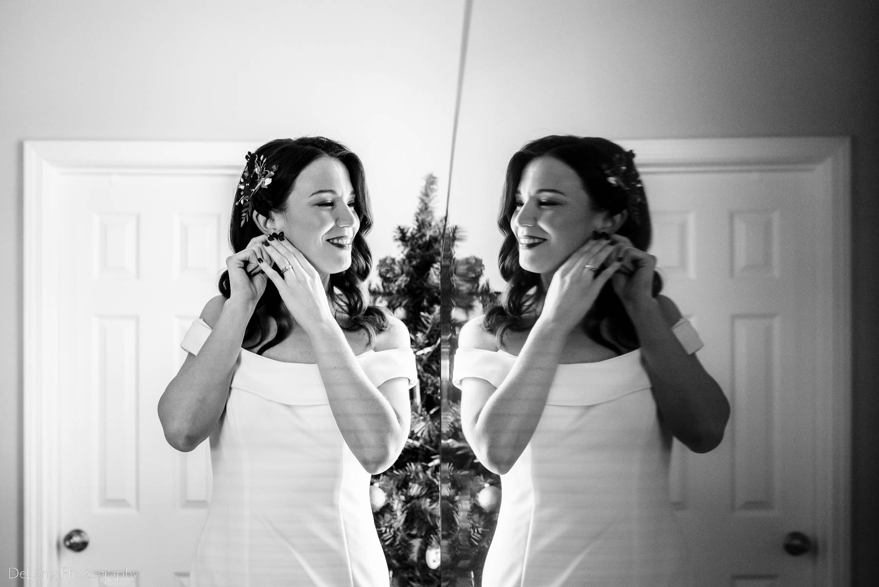 Black and white reflection photograph of a bride putting in her earrings by Charlotte wedding photographers DeLong Photography