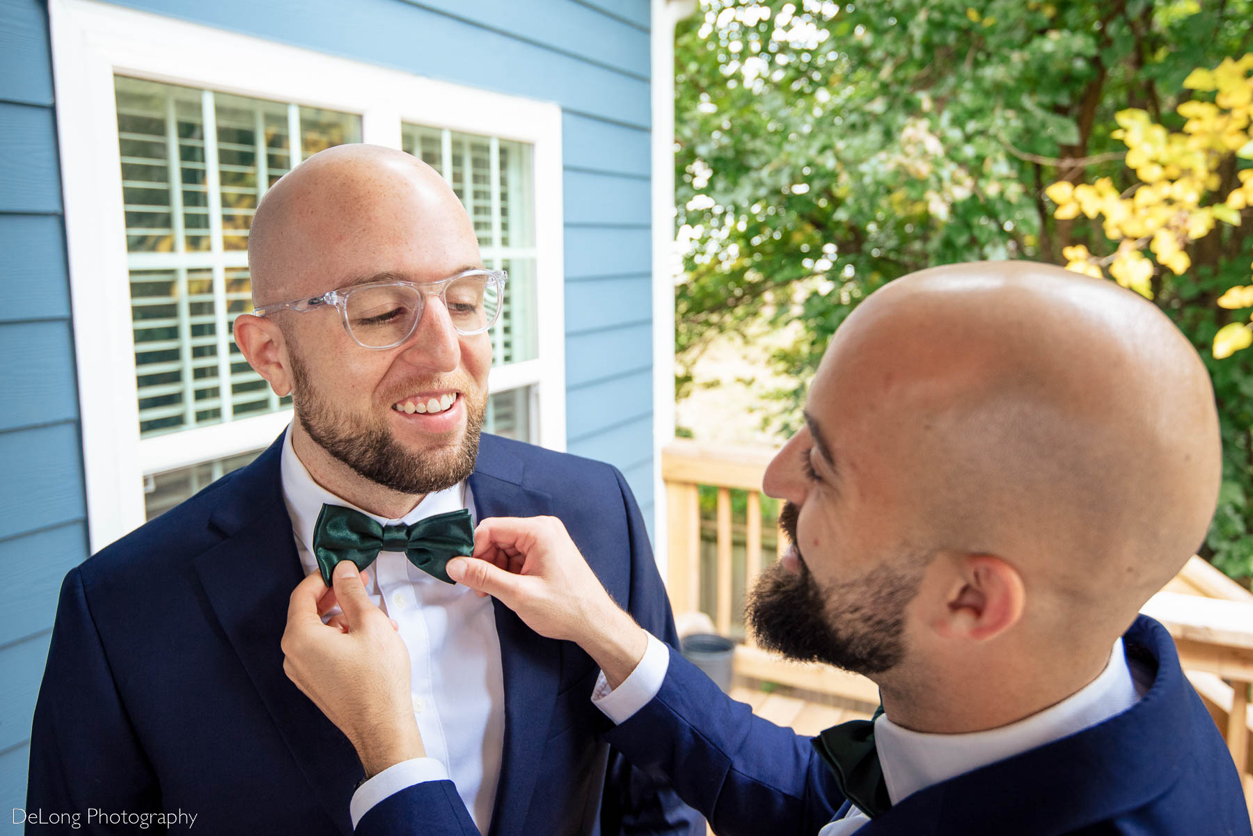 Groom having his tie adjusted while getting ready before the ceremony by Charlotte wedding photographers DeLong Photography