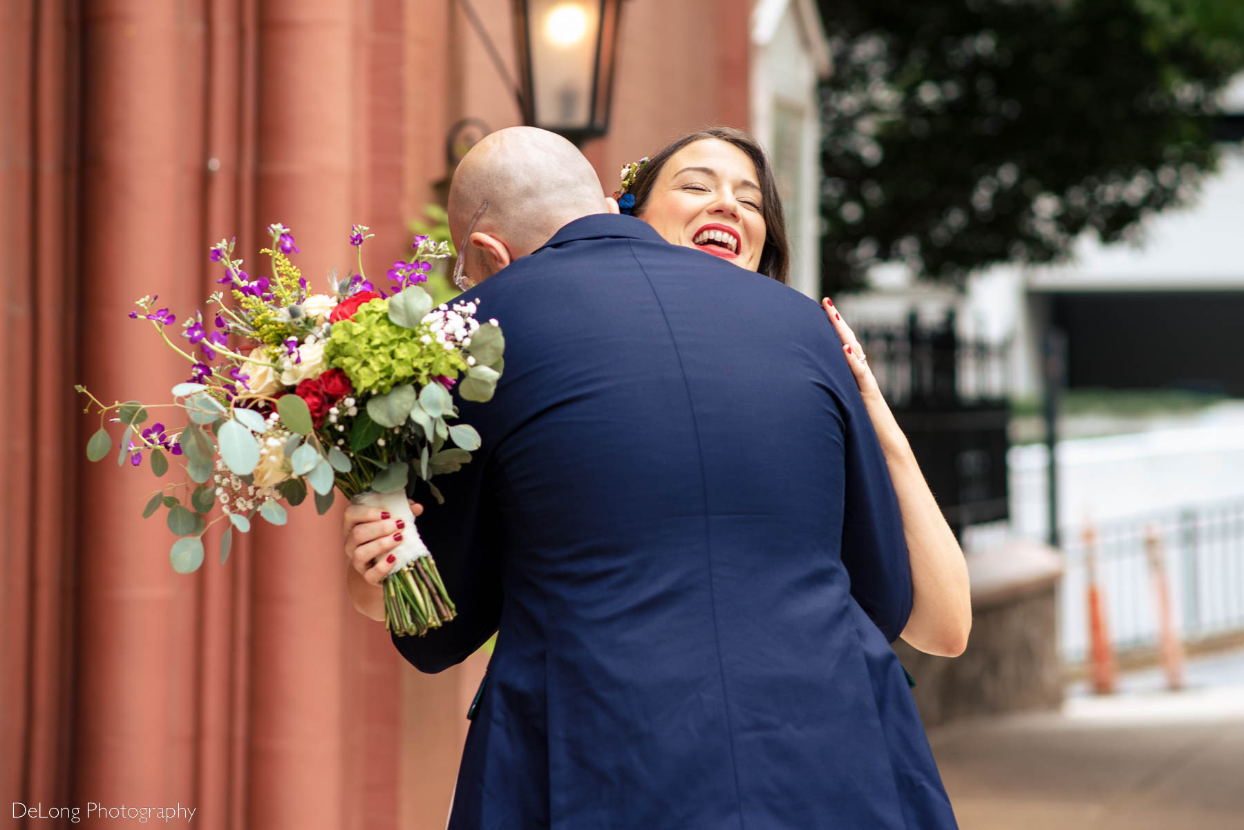 Bride smiling as her groom hugs her during their first look outside the Basilica of the Sacred Heart of Jesus in Atlanta, GA by Charlotte wedding photographers DeLong Photography