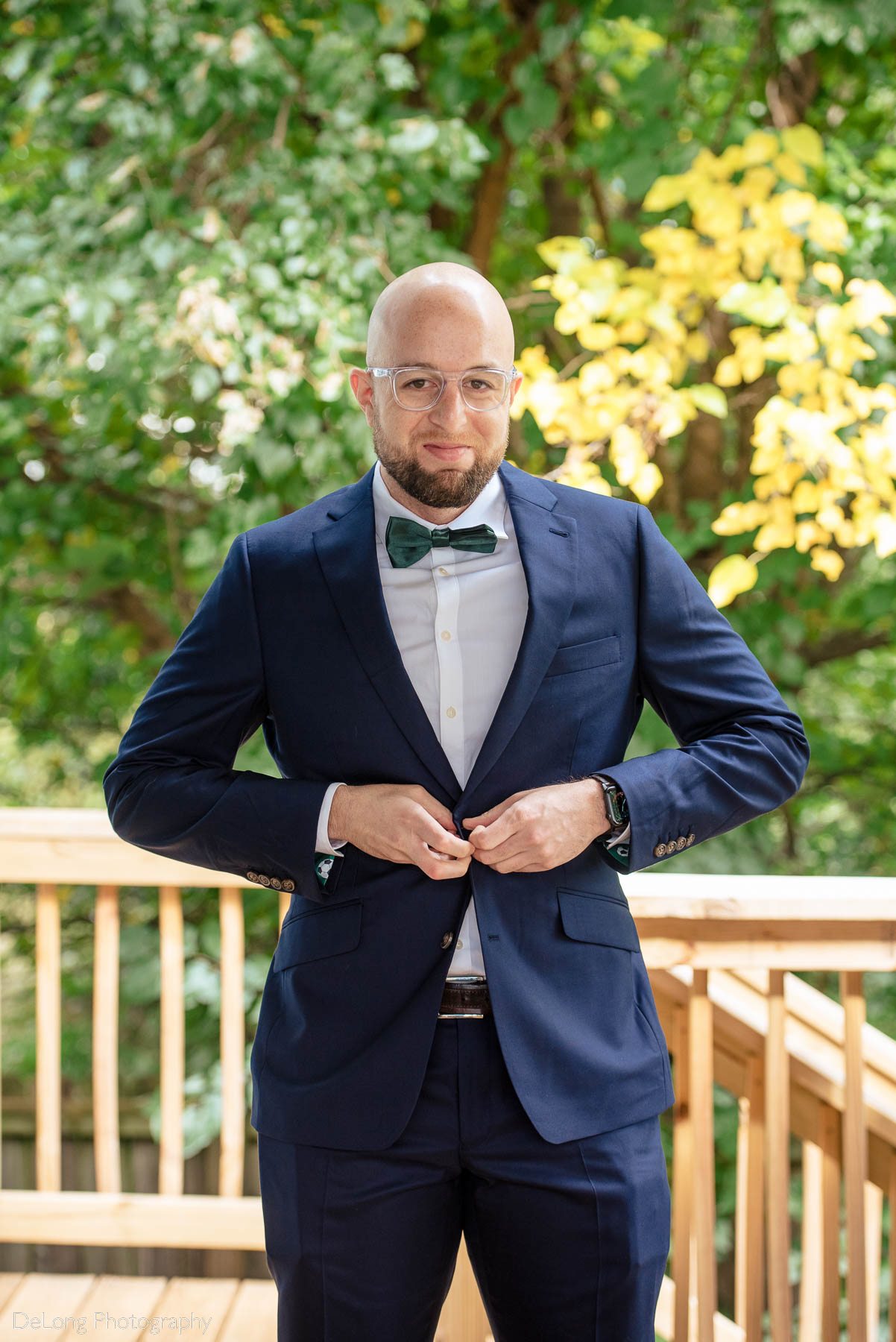 Portrait of groom buttoning his jacket by Charlotte wedding photographers DeLong Photography