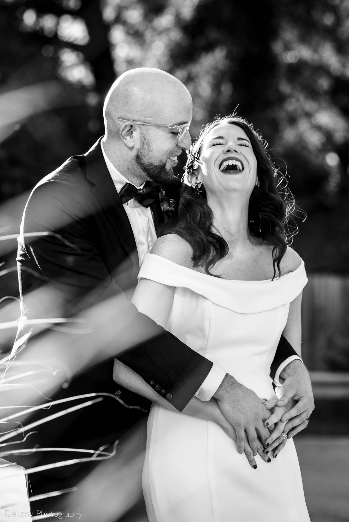 Black and white image of a smiling groom with his arms around his laughing bride outside Eventide Brewing in Atlanta, GA by Charlotte wedding photographers DeLong Photography