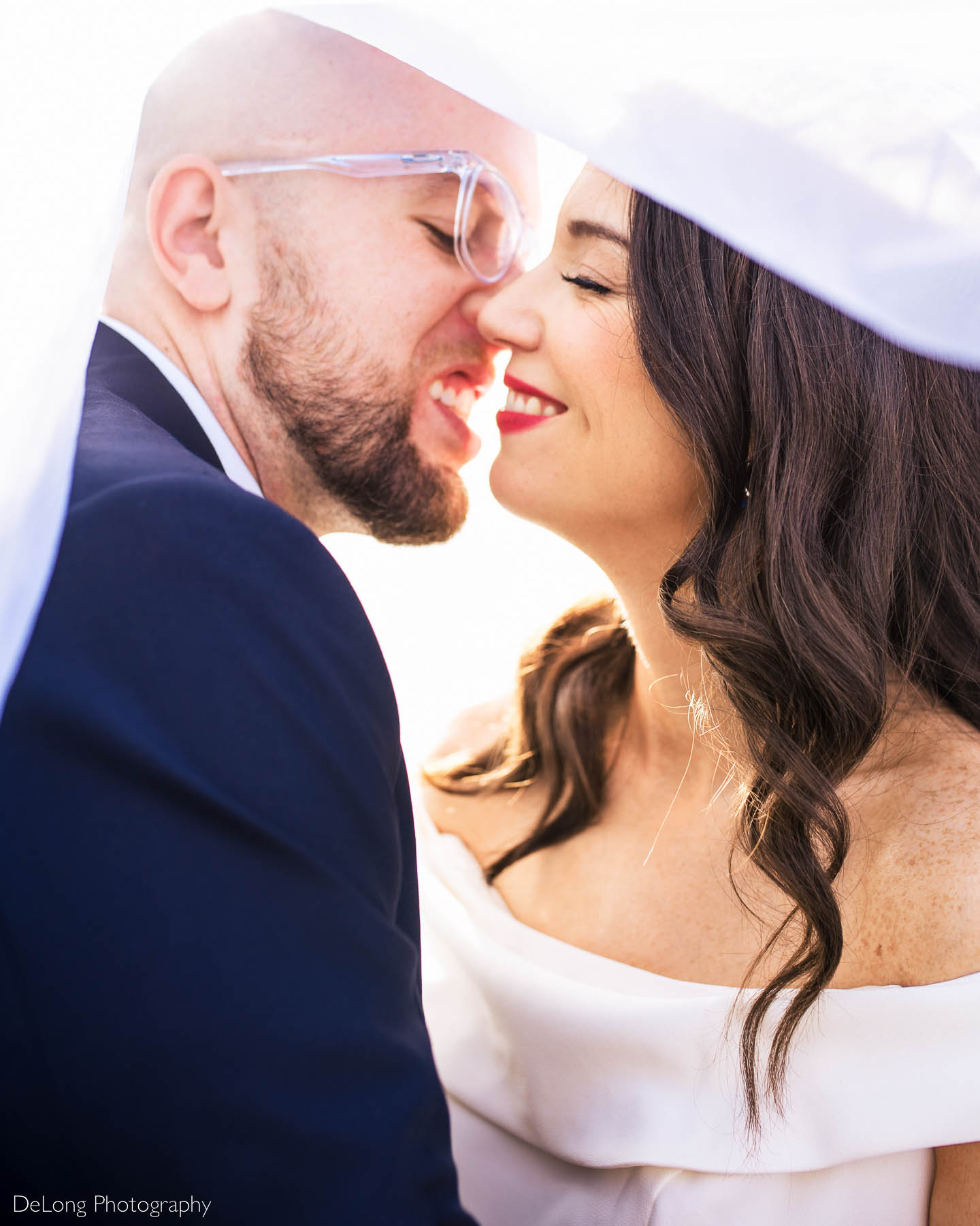 Up close photograph of a bride and groom smiling just before they kiss underneath her veil outside Eventide Brewing in Atlanta, GA by Charlotte wedding photographers DeLong Photography