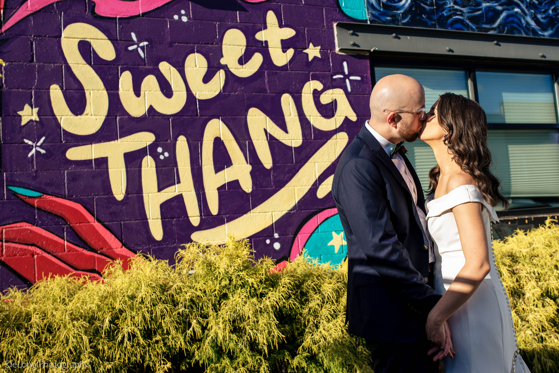 Bride and groom kissing in front of a mural that says "Sweet Thang" outside Eventide Brewing in Atlanta, GA by Charlotte wedding photographers DeLong Photography