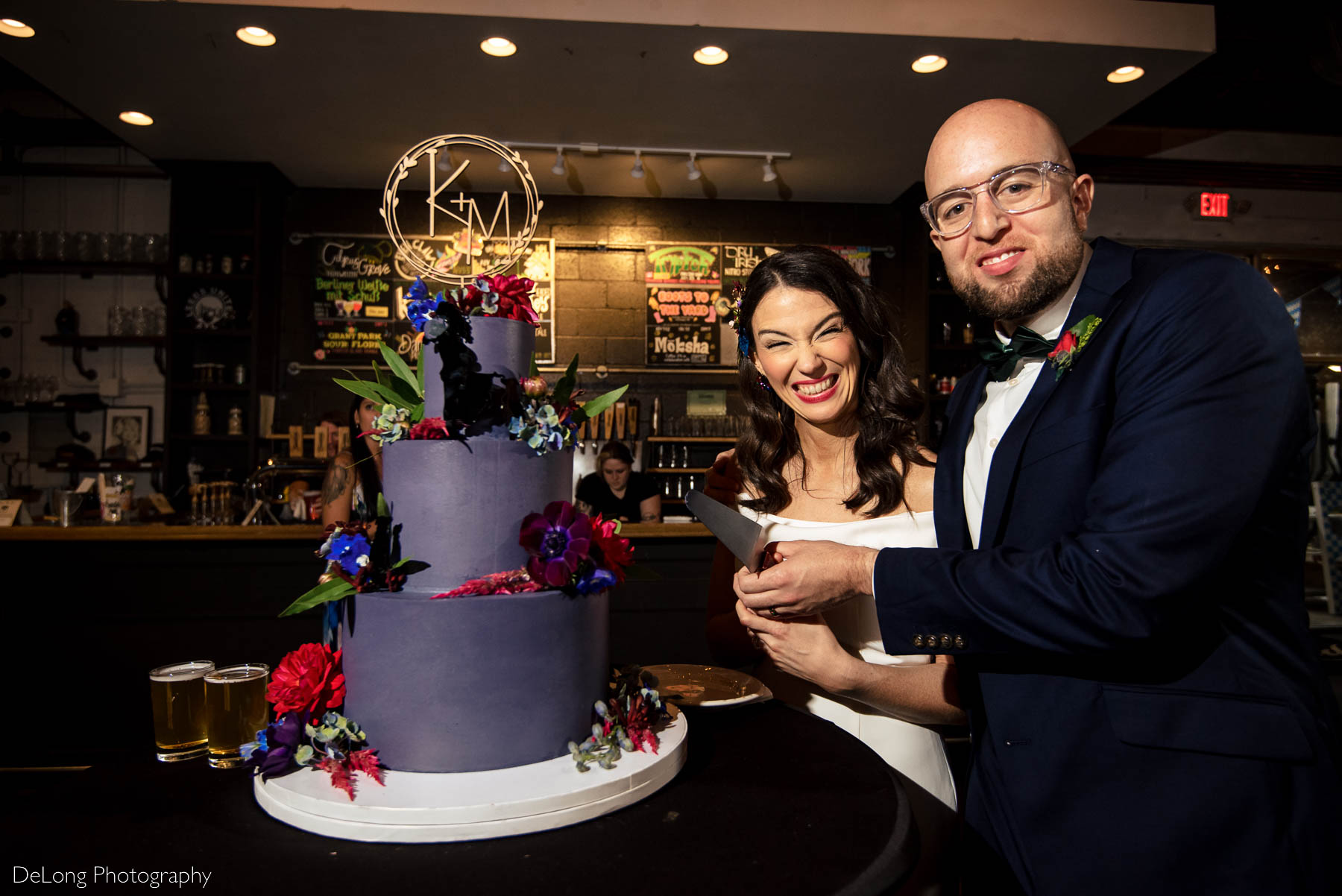 Bride and groom cutting their jewel-toned purple wedding cake by Ginger Spice Bakery at Eventide Brewing in Atlanta, GA by Charlotte wedding Photographers DeLong Photography