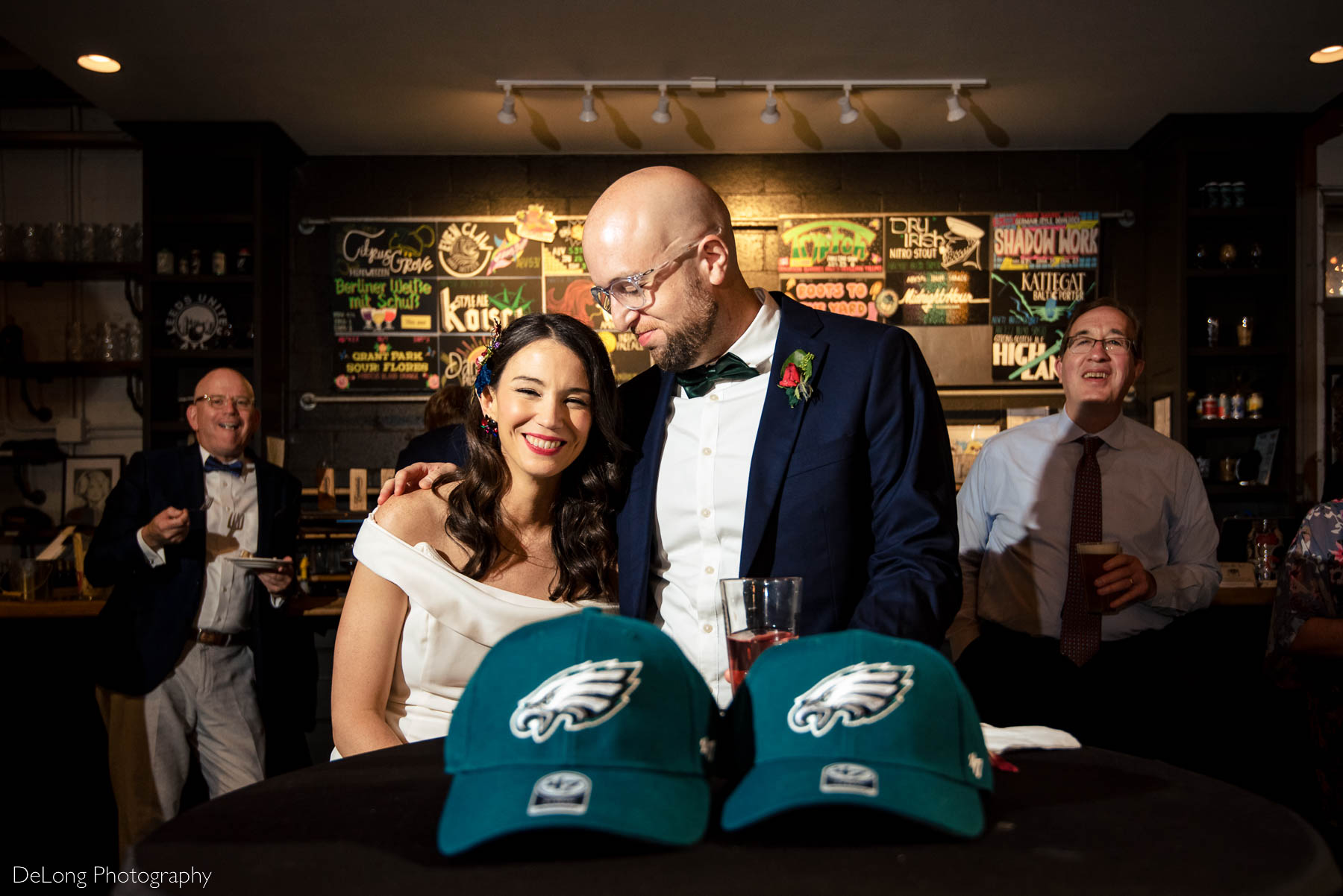 Bride and groom smiling after receiving their Atlanta Falcons hats as part of a family tradition during their wedding reception at Eventide Brewing in Atlanta, GA by Charlotte wedding Photographers DeLong Photography