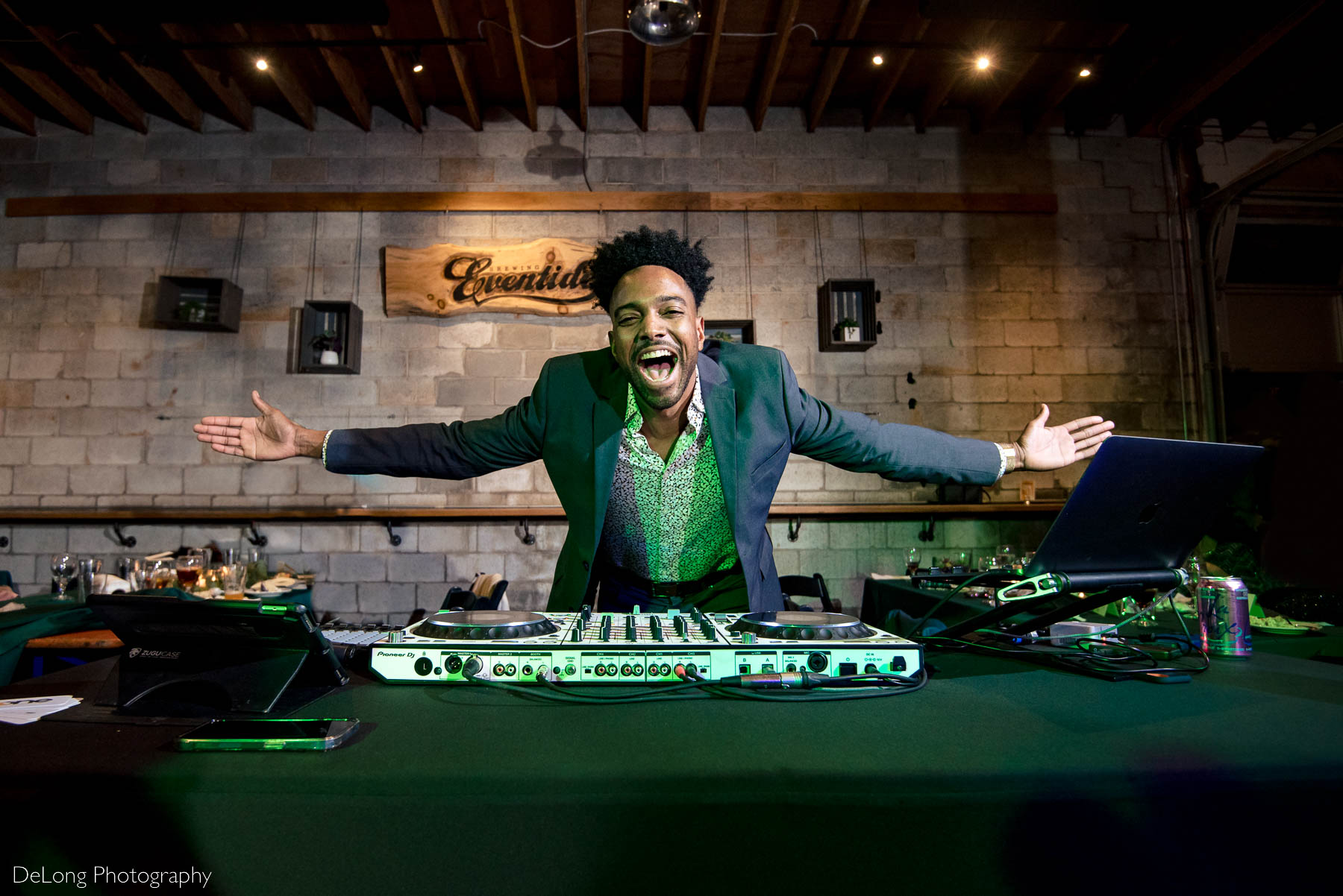 Chris from One Night Atlanta smiling with his arms wide while DJ-ing at Eventide Brewing in Atlanta, GA by Charlotte wedding Photographers DeLong Photography