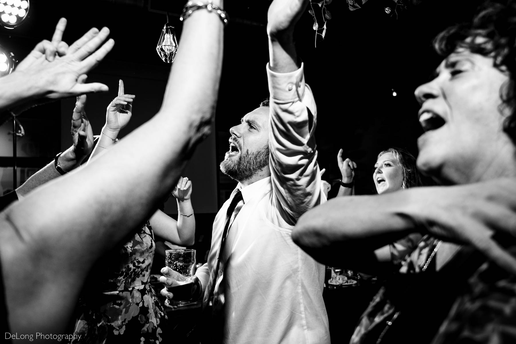 Black and white candid photo of guests singing and dancing during a wedding reception at Eventide Brewing in Atlanta, GA by Charlotte wedding Photographers DeLong Photography