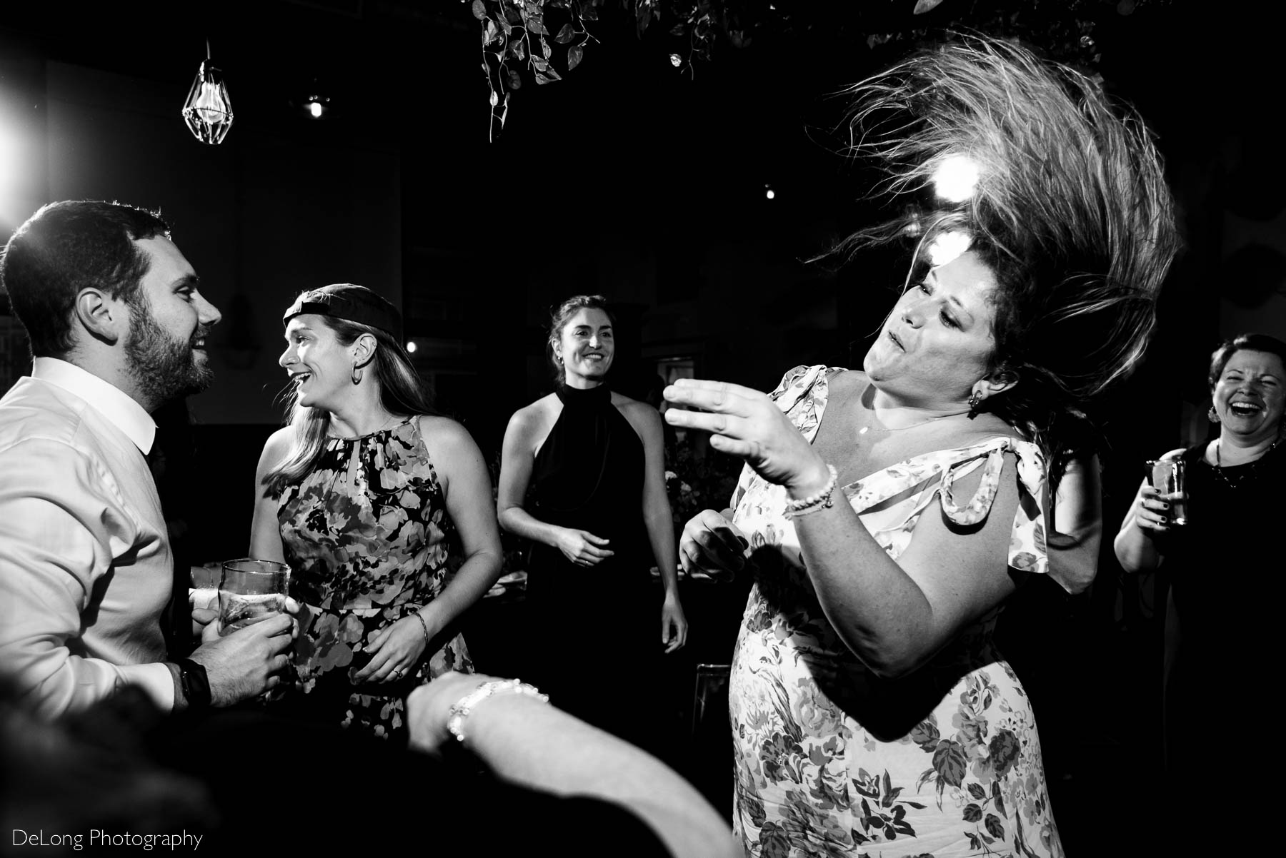 Black and white photo of a guest's long hair captured in the air while dancing at a wedding reception at Eventide Brewing in Atlanta, GA by Charlotte wedding Photographers DeLong Photography