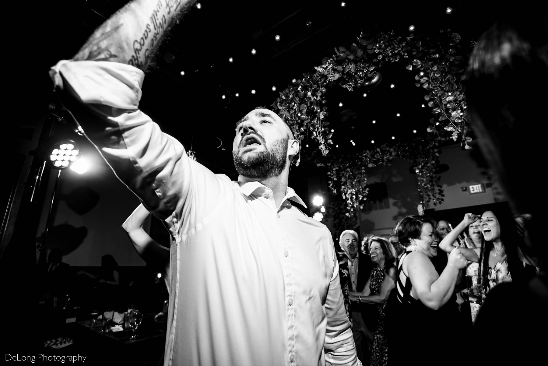 Black and white up close photo of a guest singing on the dance floor of a wedding reception at Eventide Brewing in Atlanta, GA by Charlotte wedding Photographers DeLong Photography