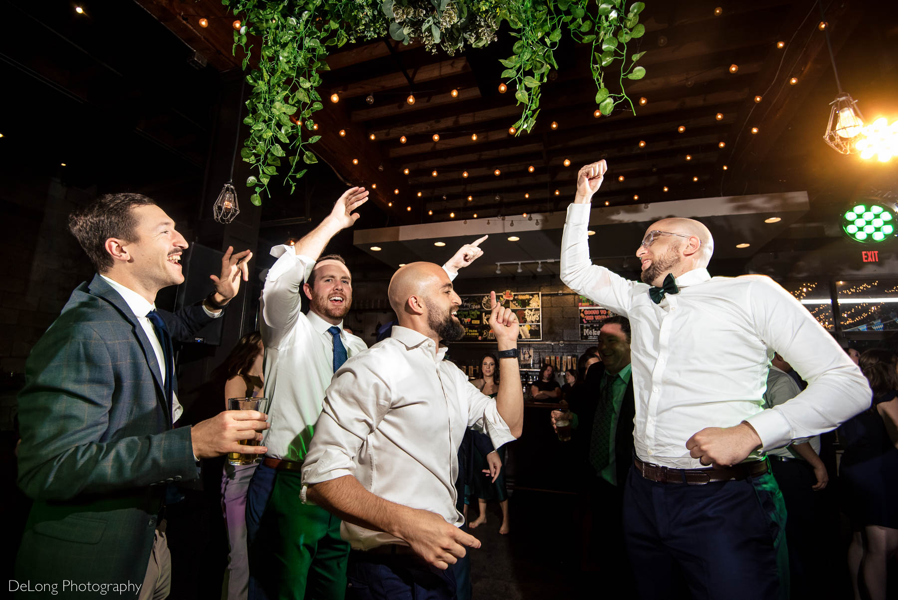 Groom and his groomsmen jumping up and down dancing at a wedding reception at Eventide Brewing in Atlanta, GA by Charlotte wedding Photographers DeLong Photography
