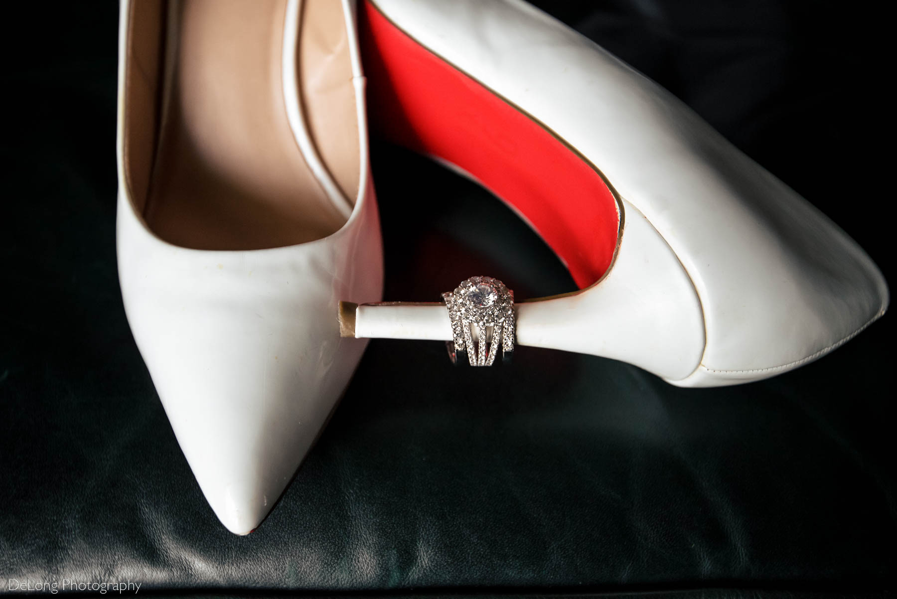 The bride's Christian Louboutin white leather stilettos with her engagement ring and wedding bands on one of the heels at the Ballantyne Hotel by Charlotte wedding photographers DeLong Photography 