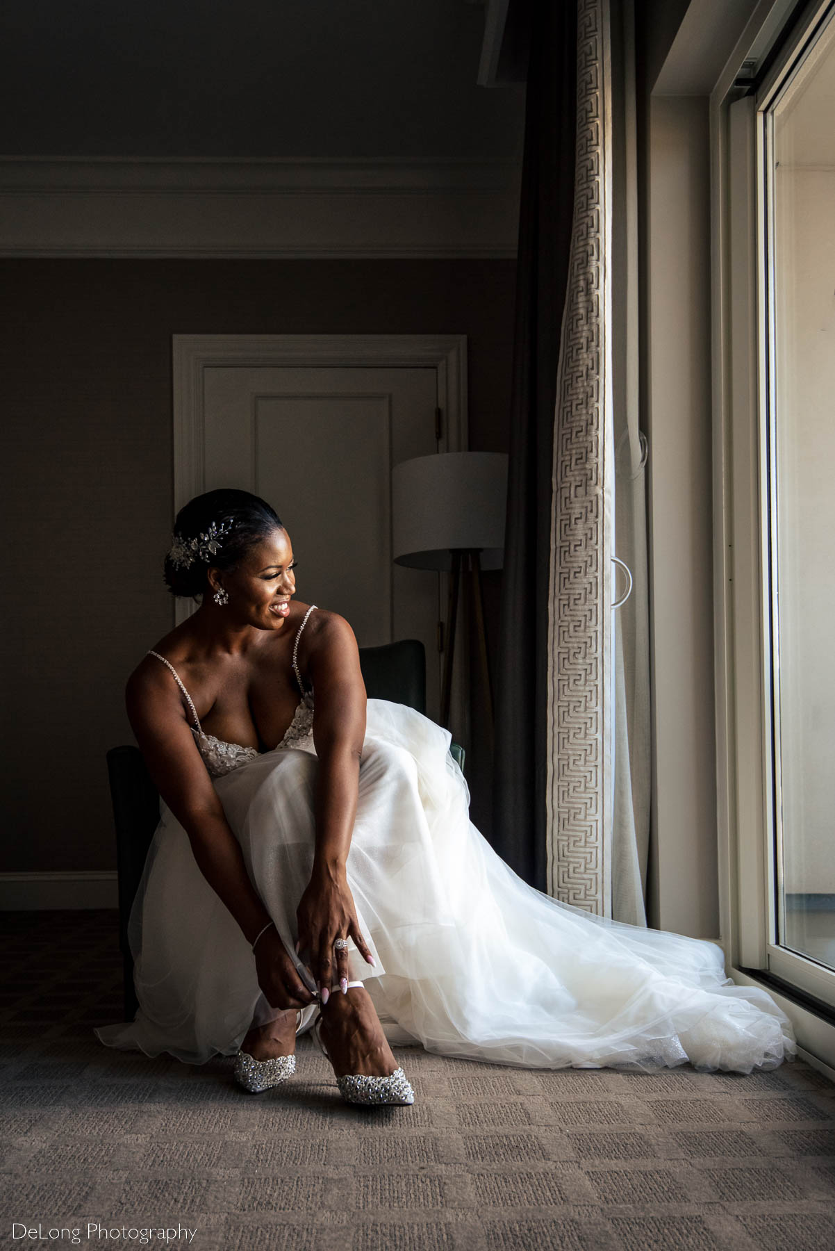 Documentary style portrait of the bride smiling while putting on her shoes at the Ballantyne Hotel by Charlotte wedding photographers DeLong Photography