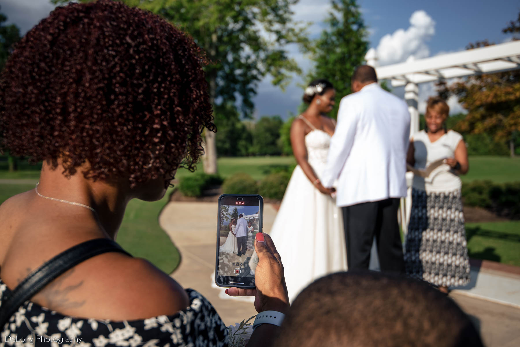 A photograph of the bride's best friend's phone showing their elopement being recorded at Providence Country Club by Charlotte wedding photographers DeLong Photography