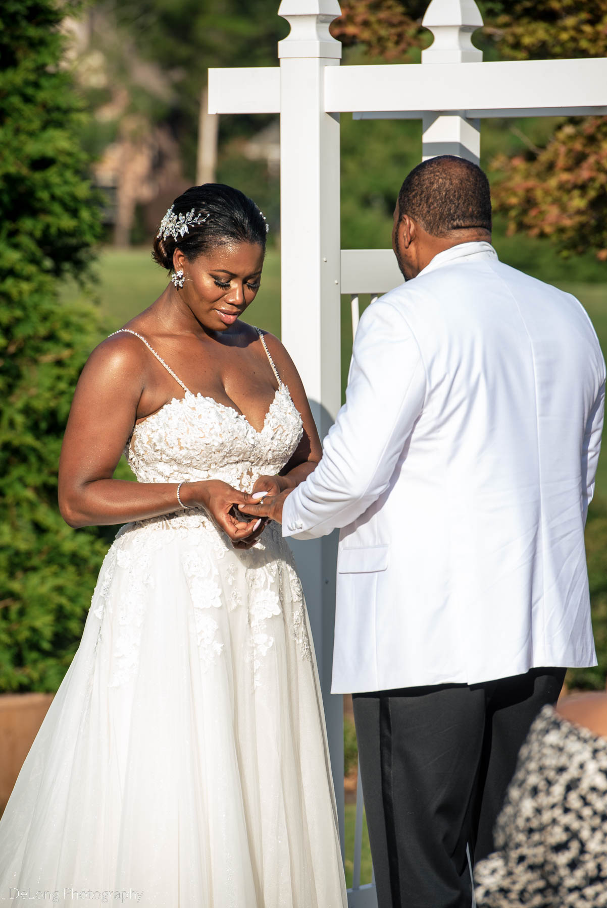 The bride placing the groom's wedding band on his finger during the wedding ceremony at at Providence Country Club by Charlotte wedding photographers DeLong Photography