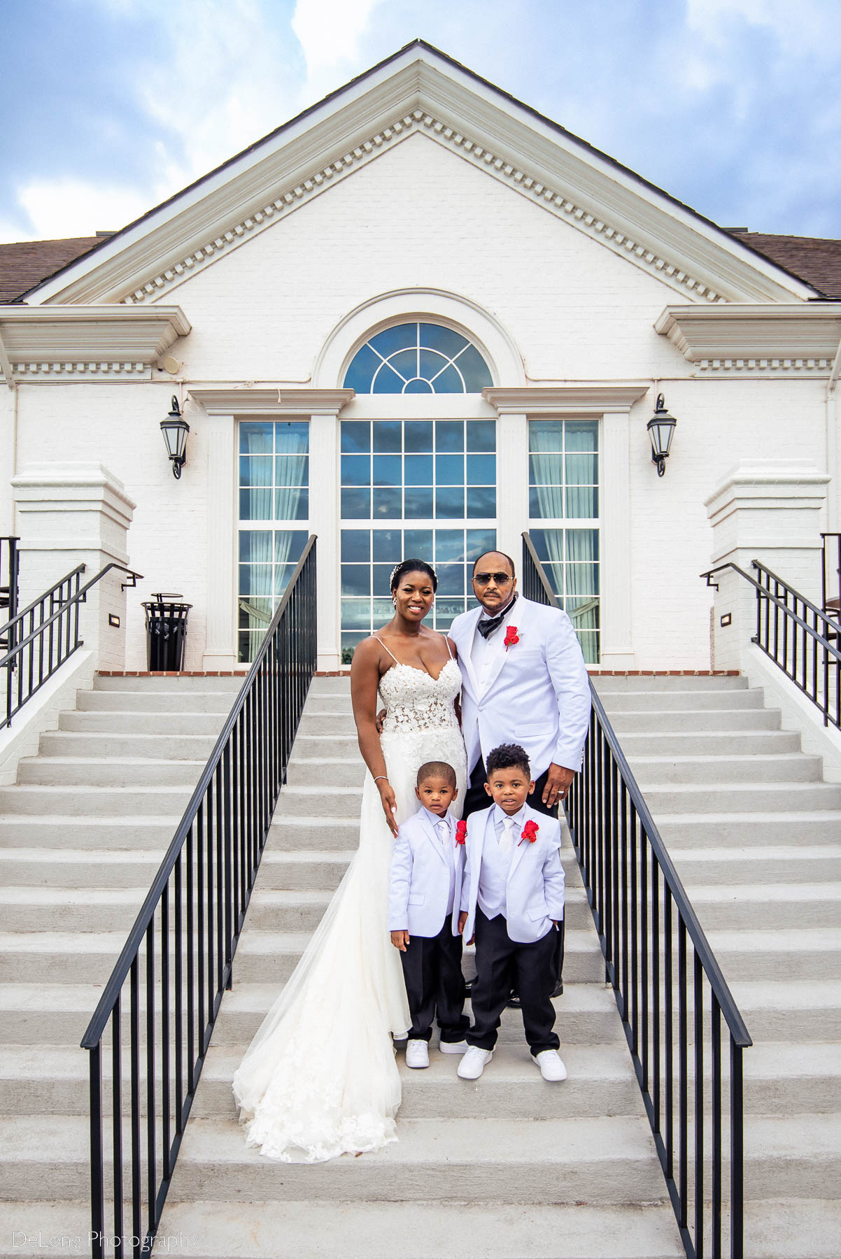 A family portrait of the bride and groom and their twin sons on the steps of the Providence Country Club by Charlotte wedding photographers DeLong Photography