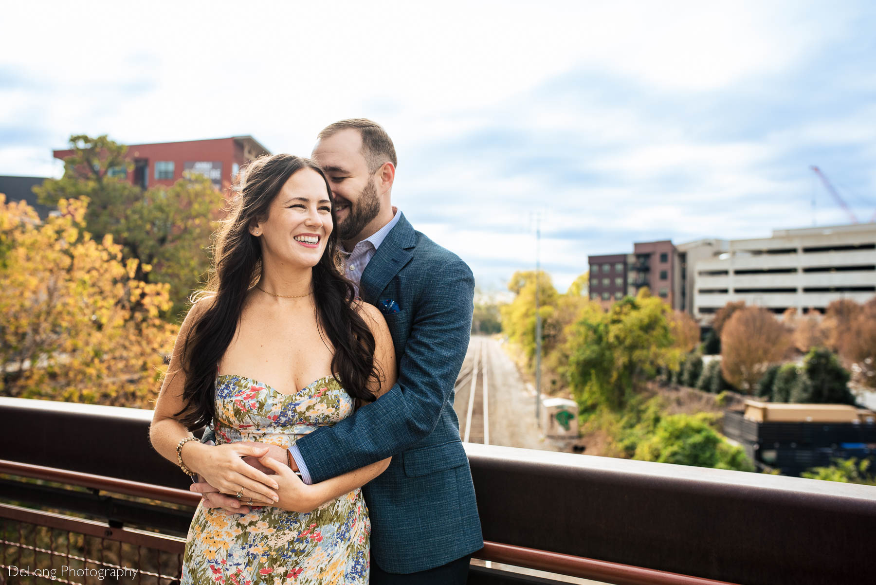 Engaged couple smiling and giggling above the railway at Westside Provisions in Atlanta by Charlotte Wedding Photographers DeLong Photography