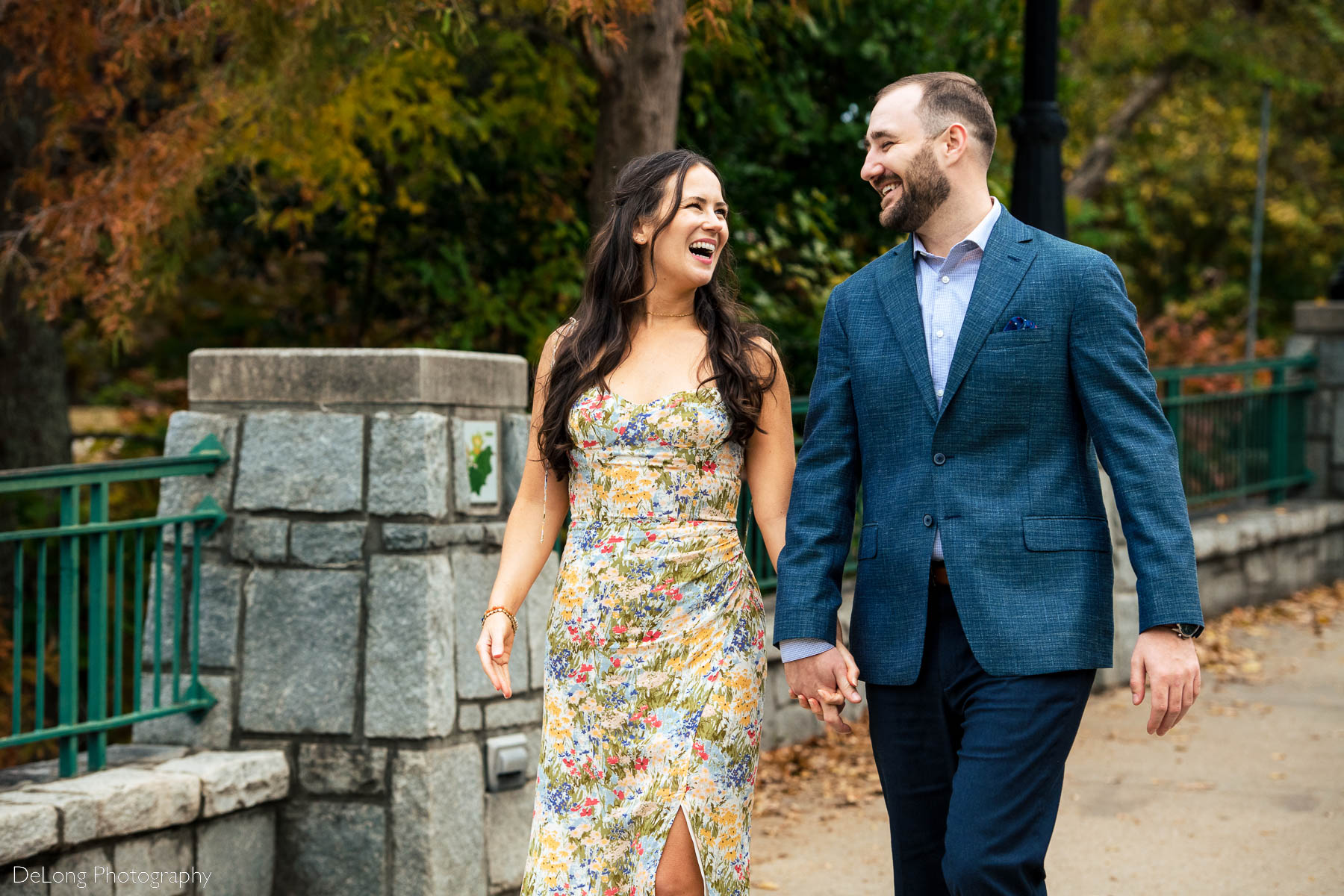 Candid photograph of engaged couple walking hand-in-hand laughing with one another at Piedmont Park in Atlanta by Charlotte wedding photographers DeLong Photography