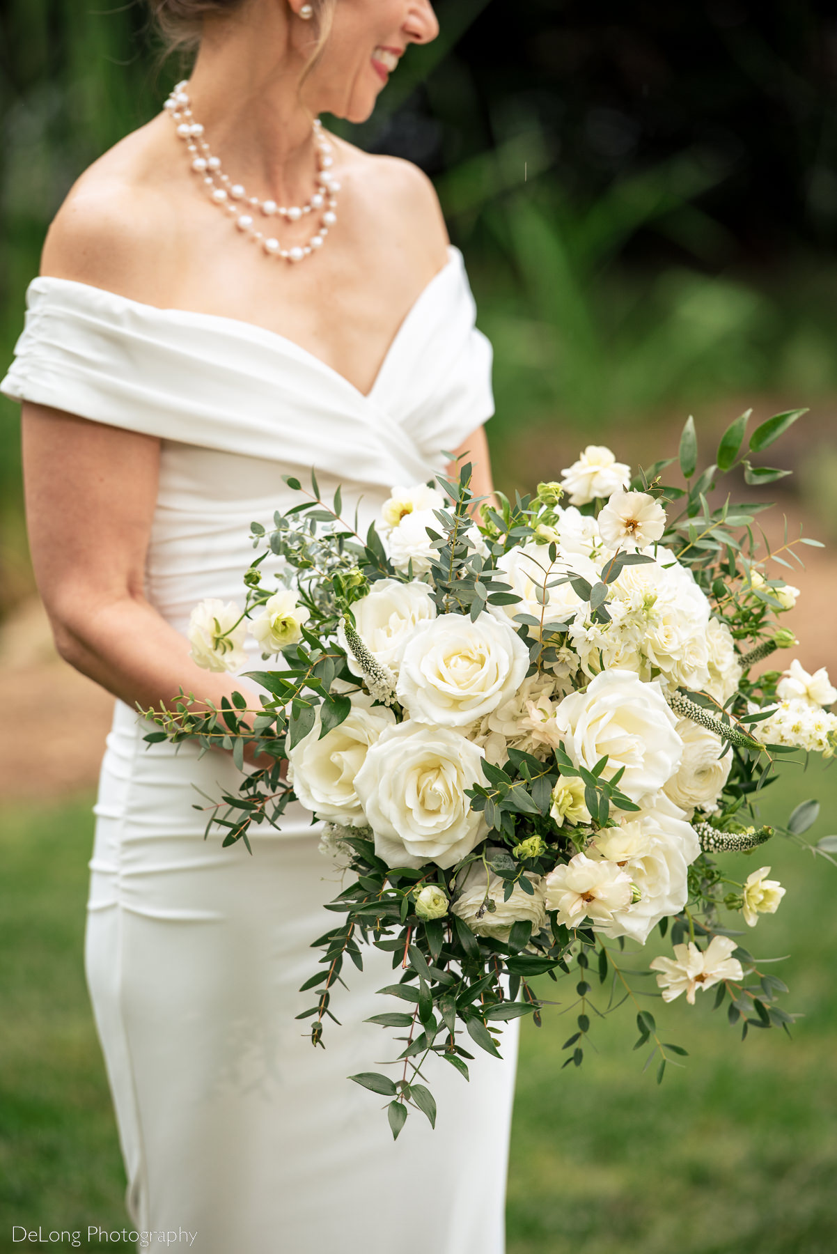 White bridal bouquet being held by bride outdoors at Alexander Homestead. Photograph by Charlotte wedding photographers DeLong Photography.