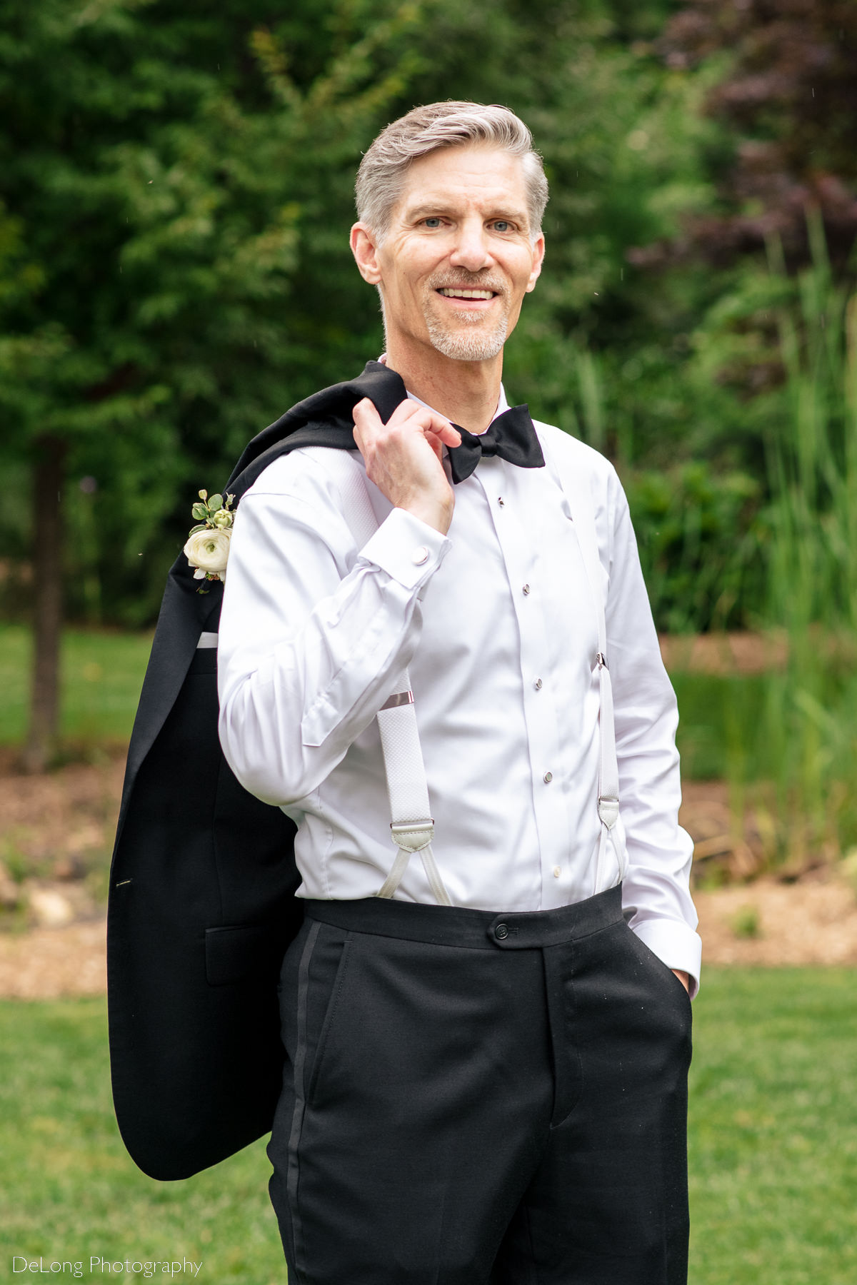 Casual groom portrait. He has his jacket draped over his shoulder. Photograph by Charlotte wedding photographers DeLong Photography.