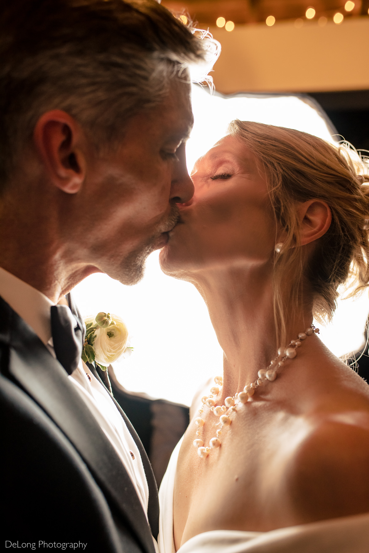 Up close nighttime portrait of a bride and groom kissing in the gazebo of Alexander Homestead. Photograph by Charlotte wedding photographers DeLong Photography.