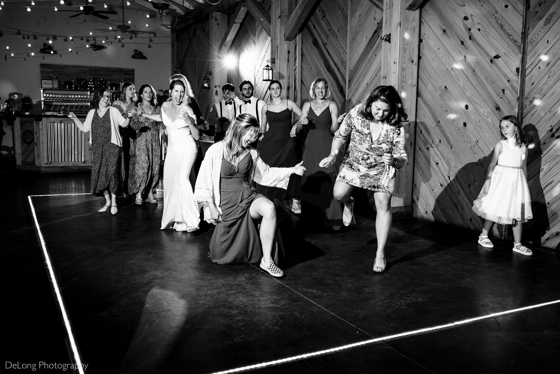 Black and white candid dancing photograph during a wedding reception at Alexander Homestead. Photograph by Charlotte wedding photographers DeLong Photography.