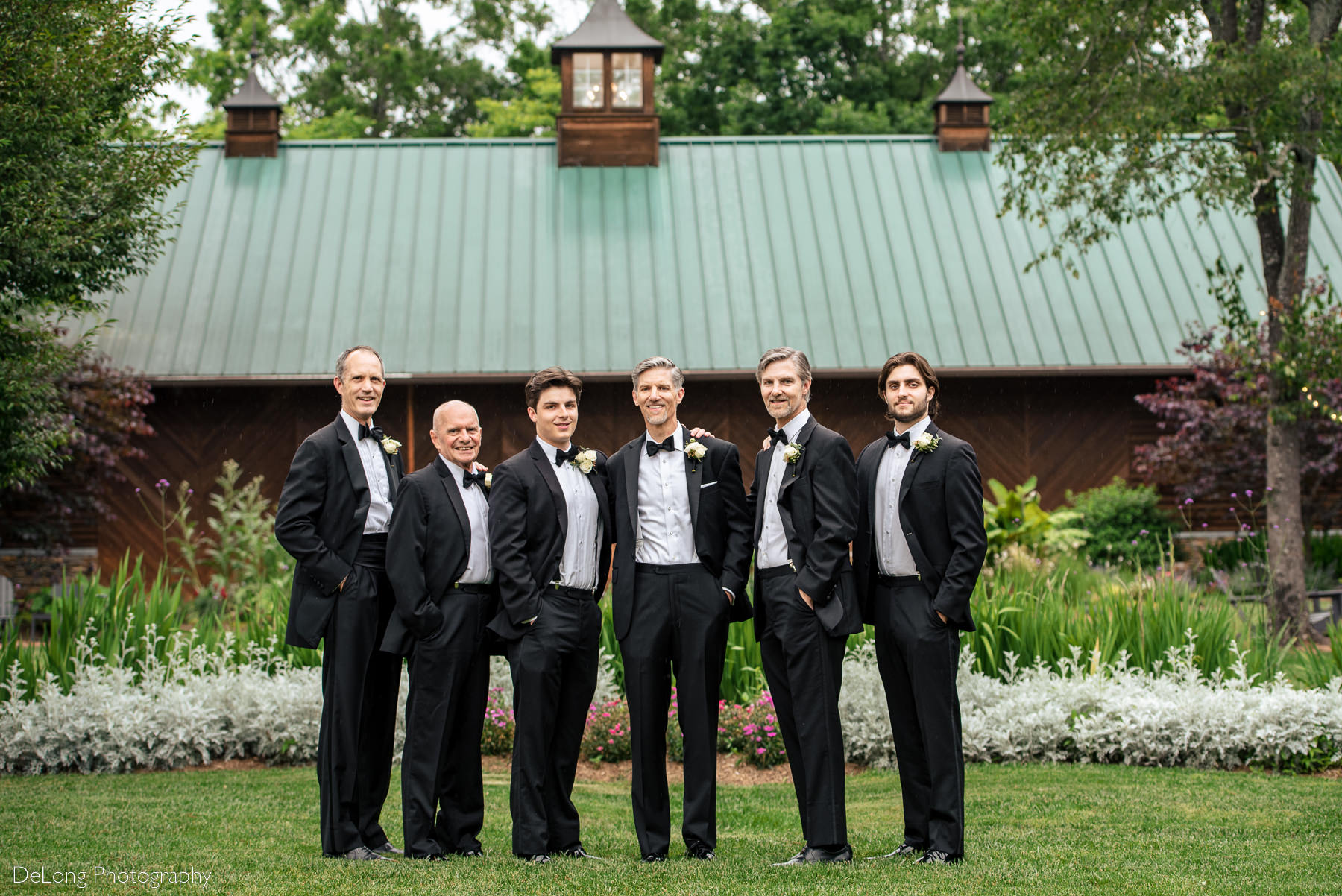 Portrait of groom with groomsmen outside in the garden at Alexander Homestead. Photograph by Charlotte wedding photographers DeLong Photography.