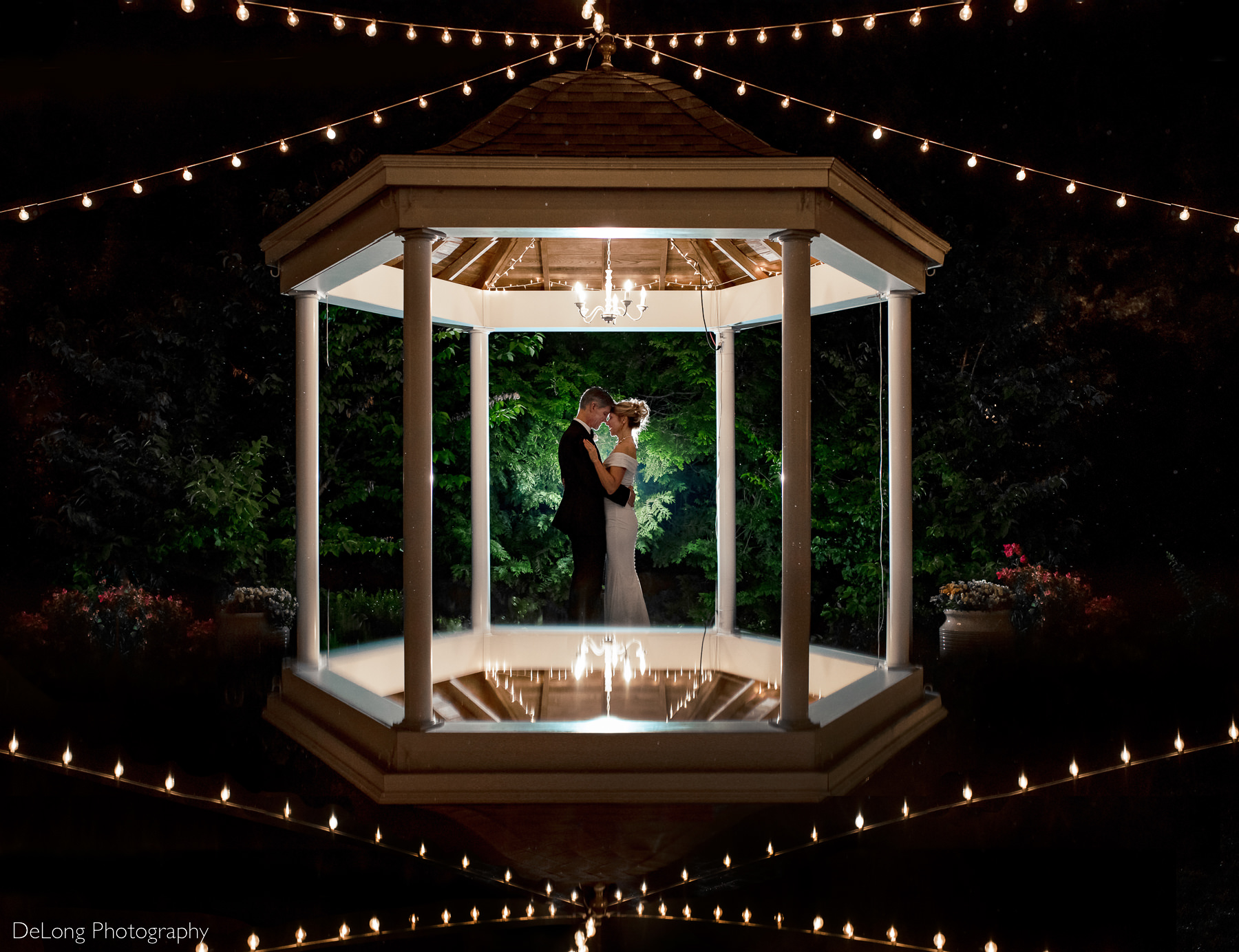 Nighttime silhouette of a couple with their foreheads together, standing inside the gazebo at Alexander Homestead. Photo by Charlotte wedding photographers DeLong Photography.