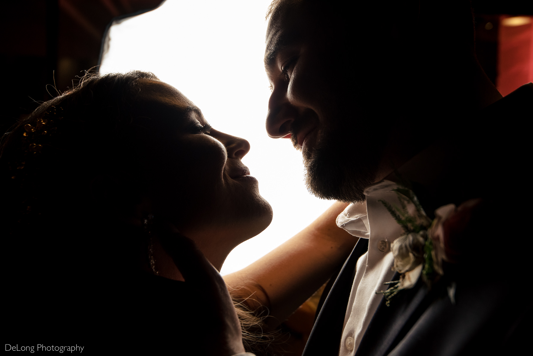 Up close portrait of a bride and groom smiling at one another, looking into each other's eyes, with their faces close together. Photograph by Charlotte wedding photographers DeLong Photography.