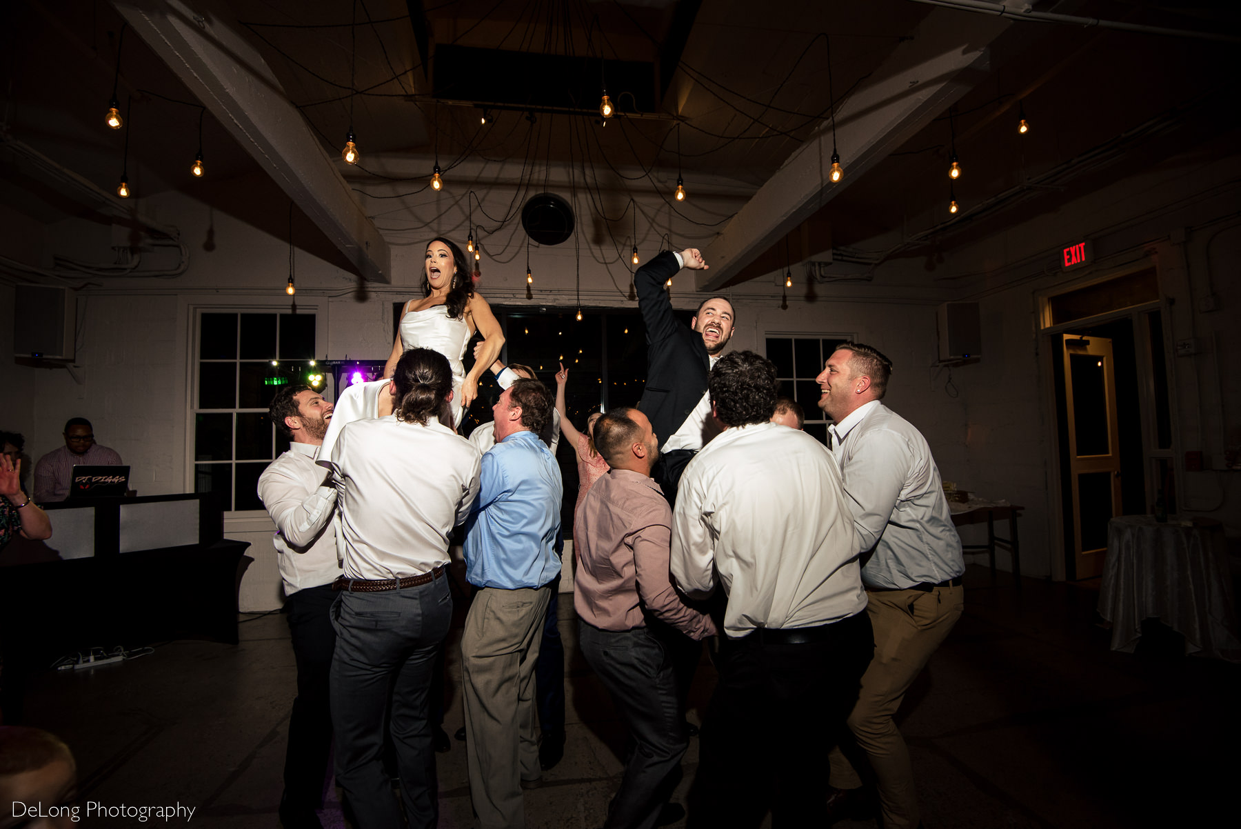 Bridge and groom being lifted in chairs during their wedding reception at Upstairs Atlanta. Photograph by Charlotte wedding photographers DeLong Photography.